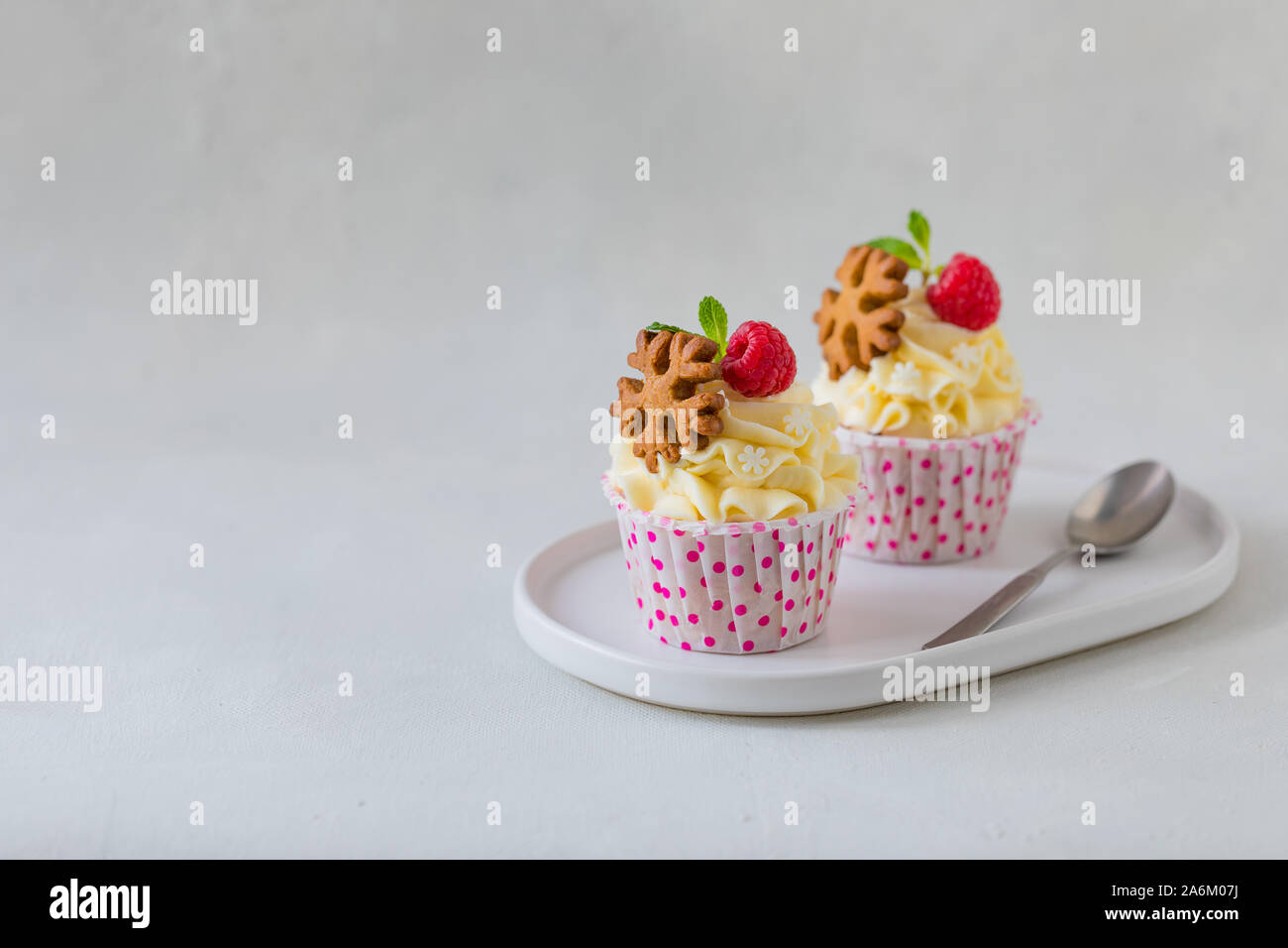 Natale tortine o muffin con panna e lampone, su sfondo concreto, tonica Foto Stock