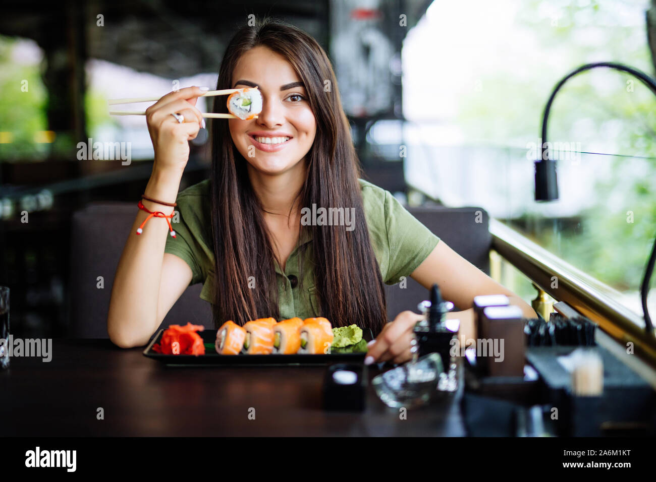 Donna bionda hanno un tempo di sushi, ella rullo di contenimento sotto i suoi occhi. Strano concetto. Foto Stock