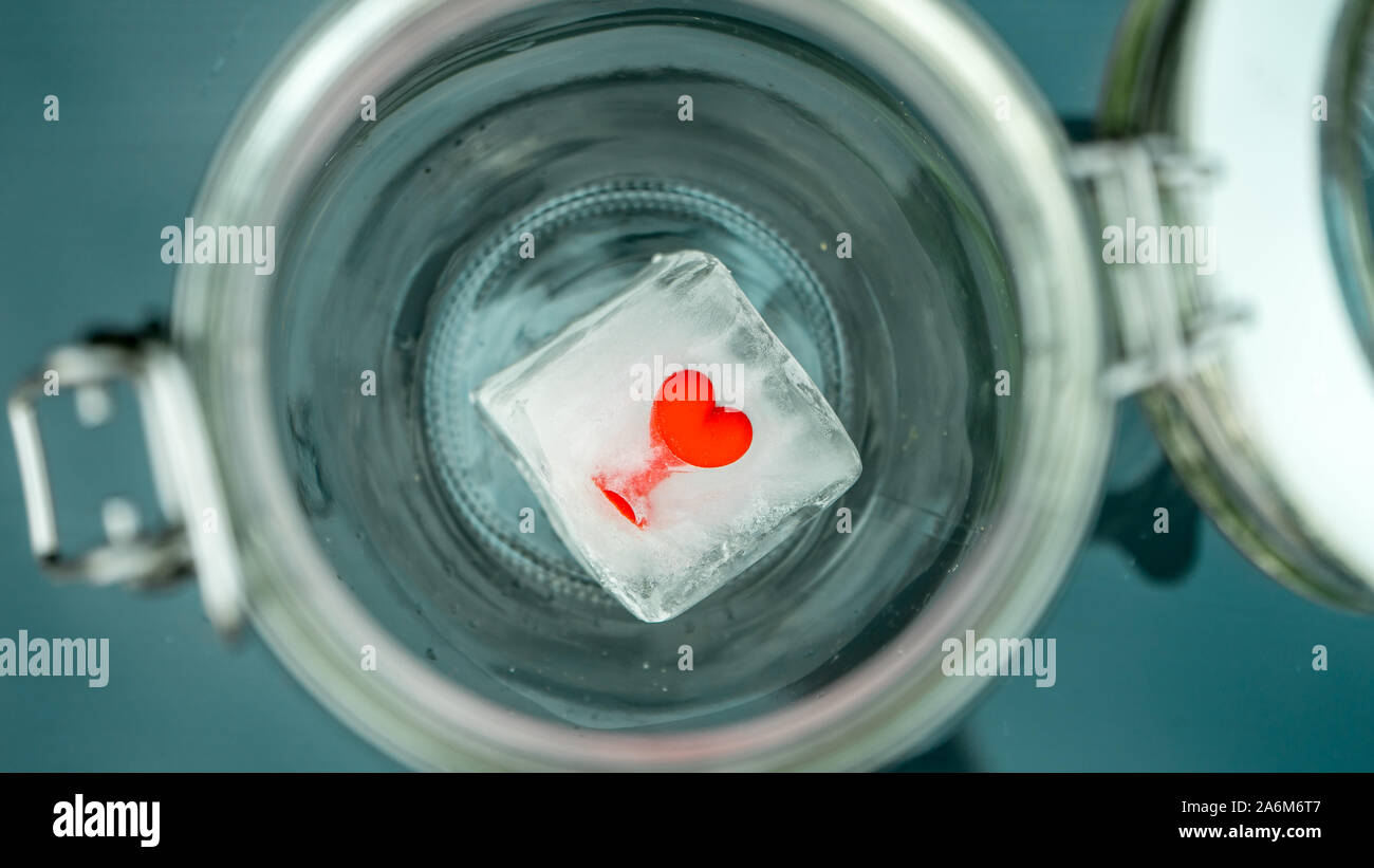 Rosso di gomma elastica cuore congelato in un cubo di ghiaccio in fusione di Sun Foto Stock