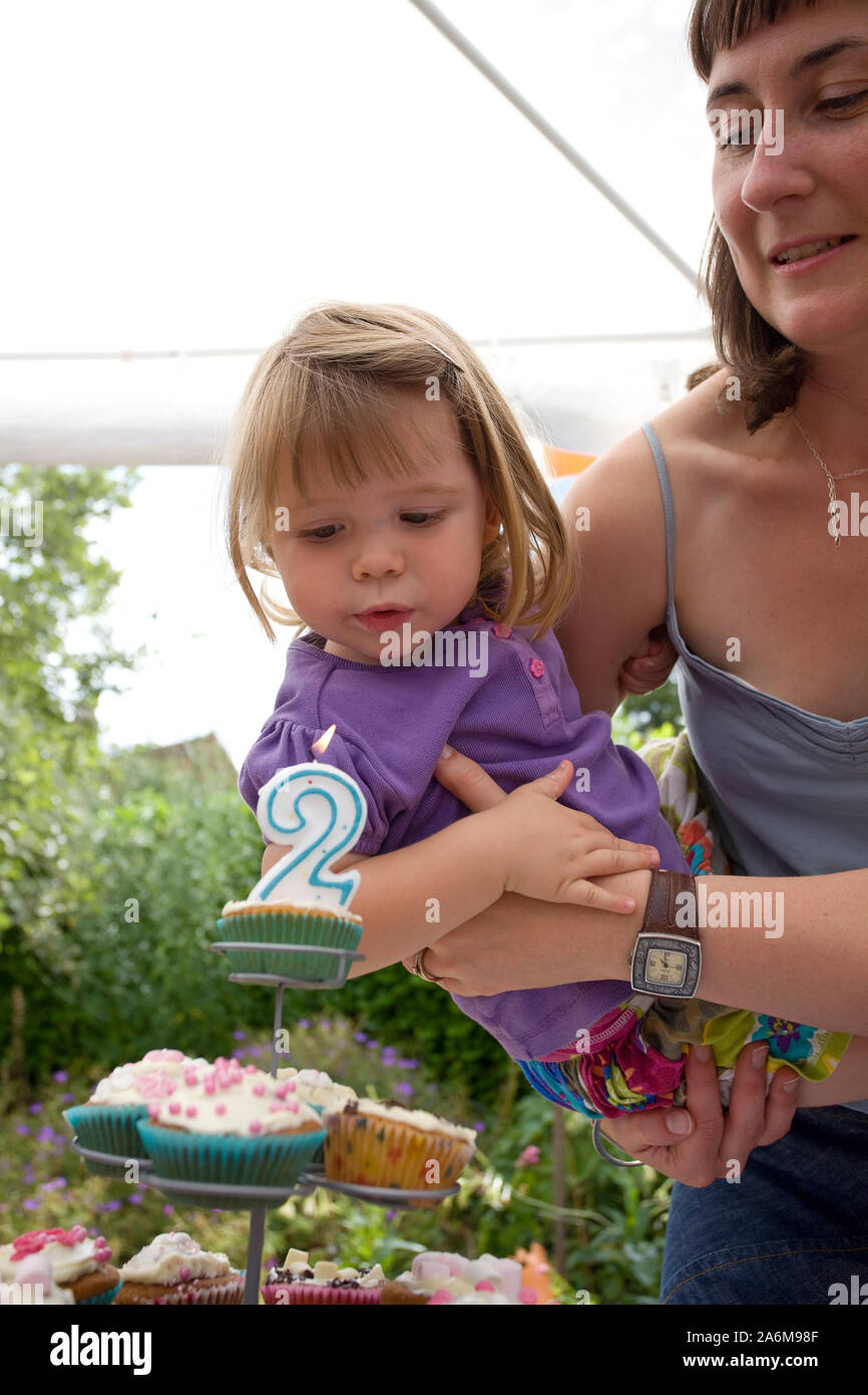 Decorazioni per compleanno invernali per bambini. 2 anni. Carino bambina in  un cardigan verde vicino torta di compleanno bianca Foto stock - Alamy