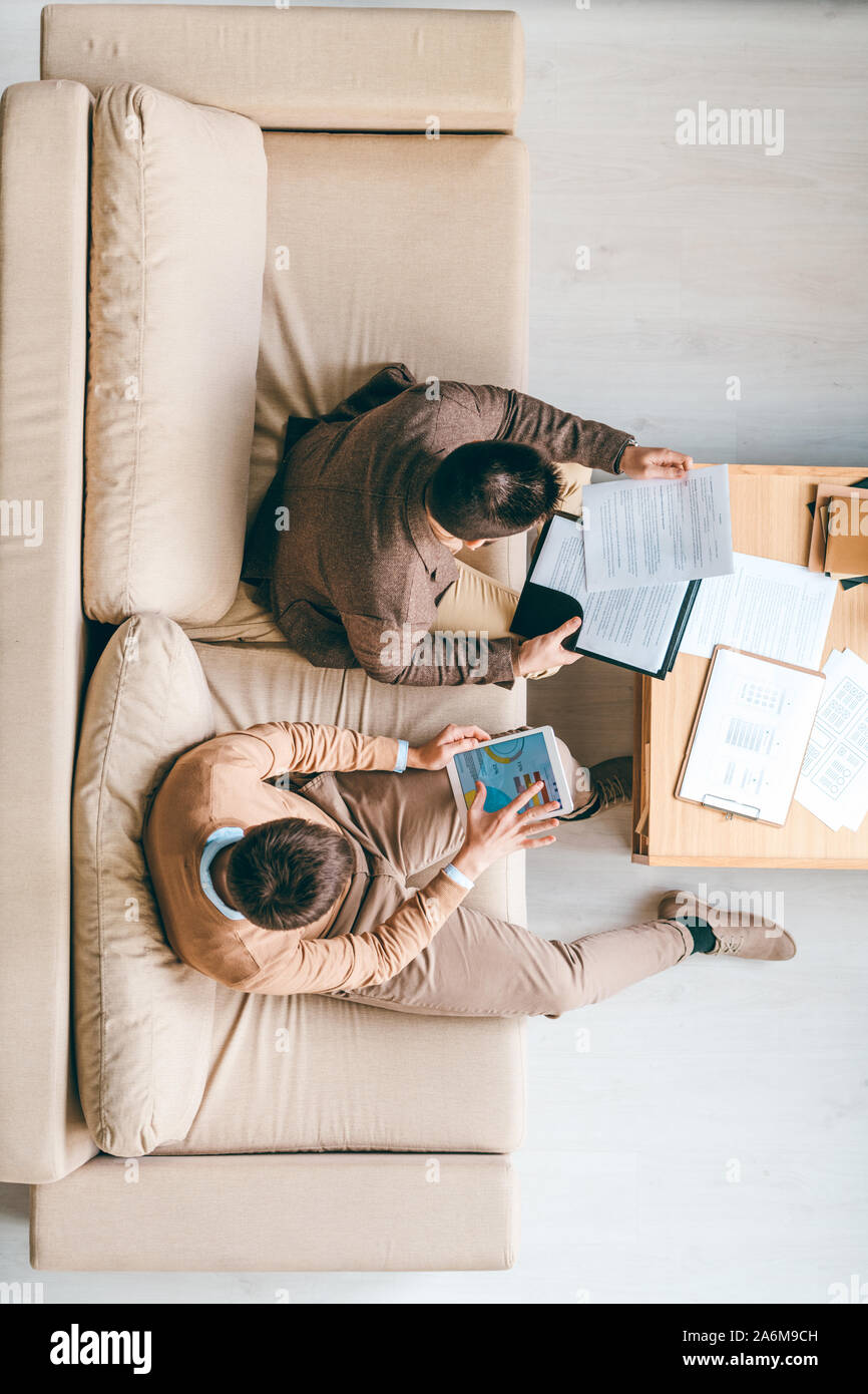 Giovani brokers seduto sul lettino in ufficio e di lavorare con le informazioni finanziarie Foto Stock