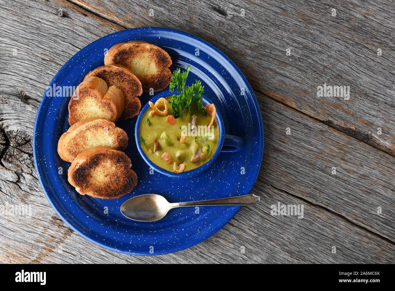 Alta angolazione di una tazza di freschi fatti in casa dividere la zuppa di piselli con pane tostato aglio su una tavola in legno rustico con copia spazio. Foto Stock