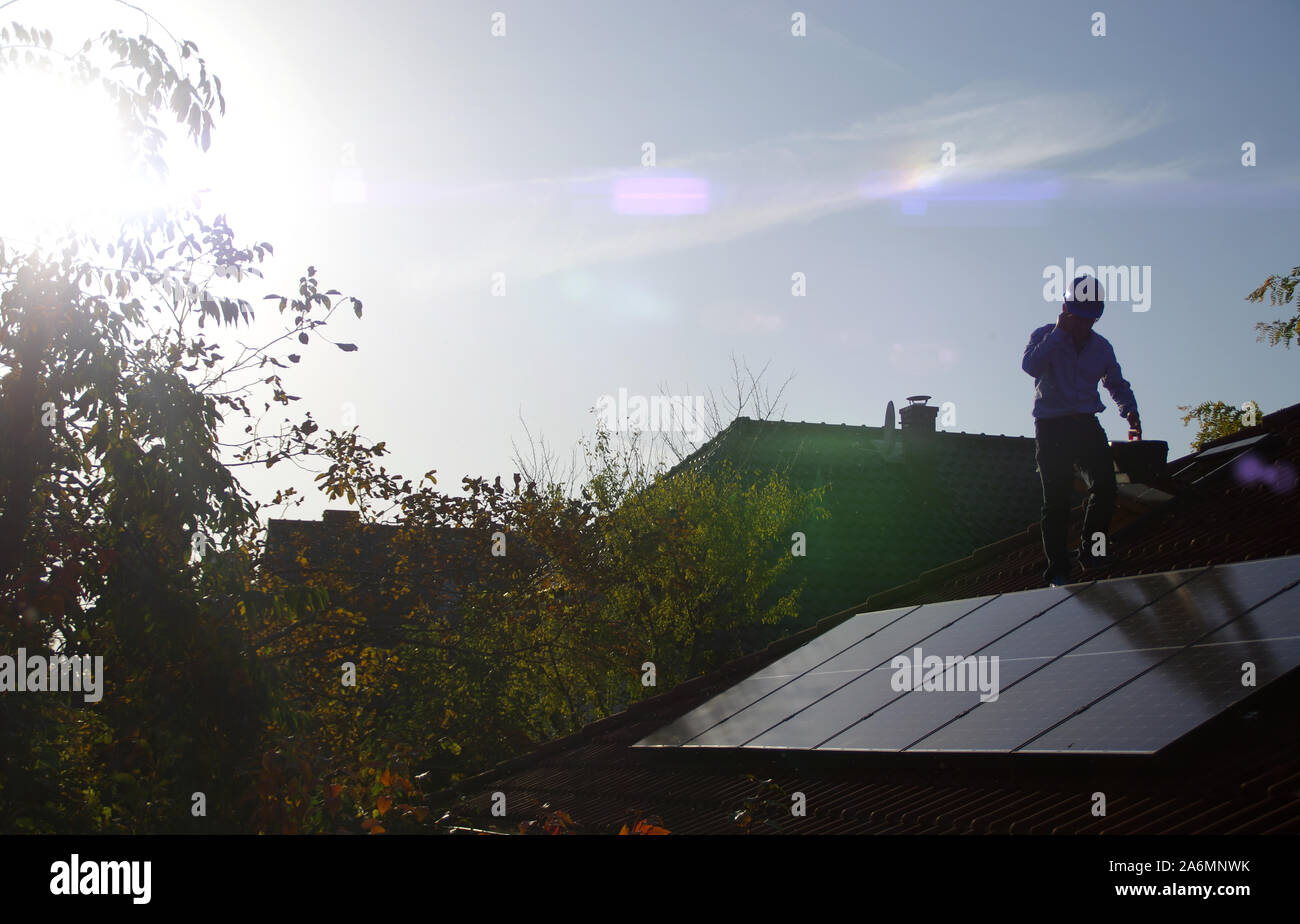 L'uomo cammina sul tetto di casa e installa pannelli solari. Il fotovoltaico, alternative e di fonti di energia rinnovabili, energia verde, ecologia e la casa di produzione di energia elettrica Foto Stock
