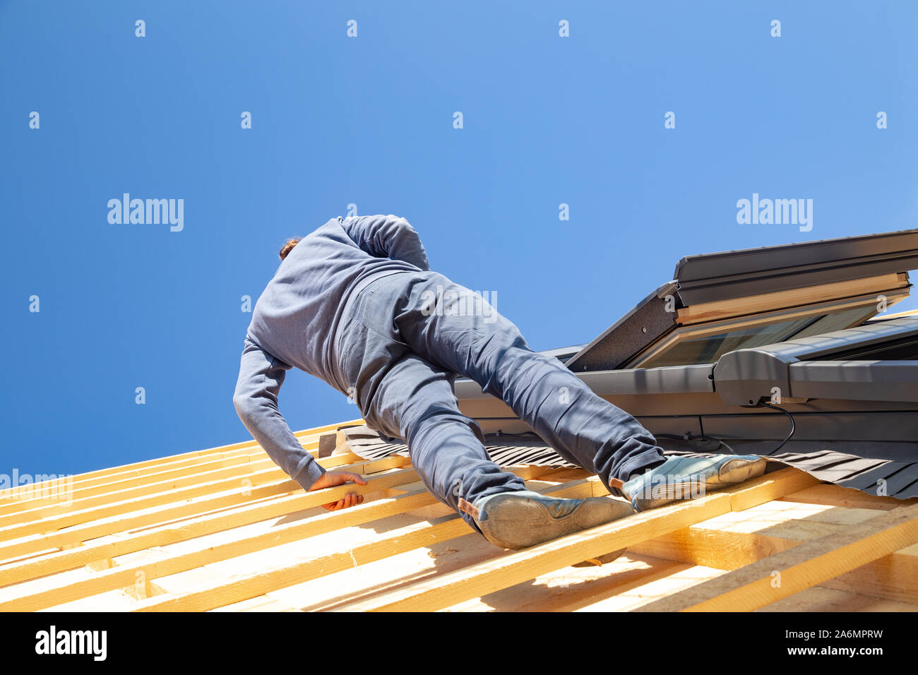 Giovane falegname installando un lucernario su un tetto di legno architrave Foto Stock