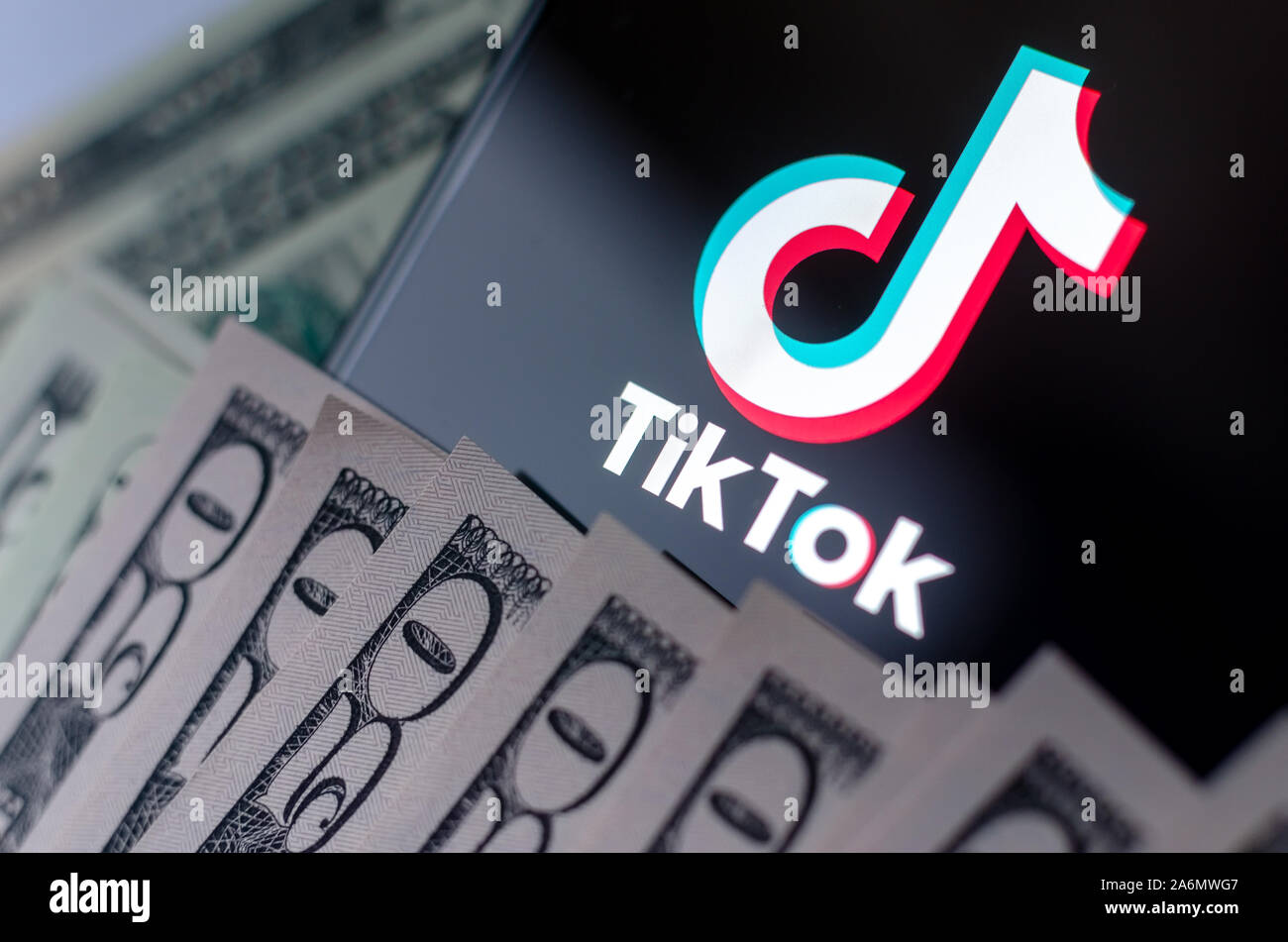TikTok logo app sullo schermo dello smartphone e US Dollar Bills accanto ad essa. Foto Stock