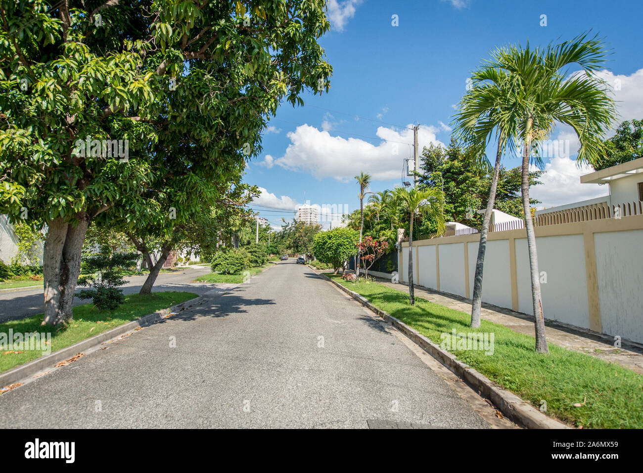 Punta Cana, Repubblica Dominicana; 11 aprile 2014: Strada asfaltata con poco traffico automobilistico, con giardinieri sui marciapiedi e le divisioni di strada con alberi Foto Stock