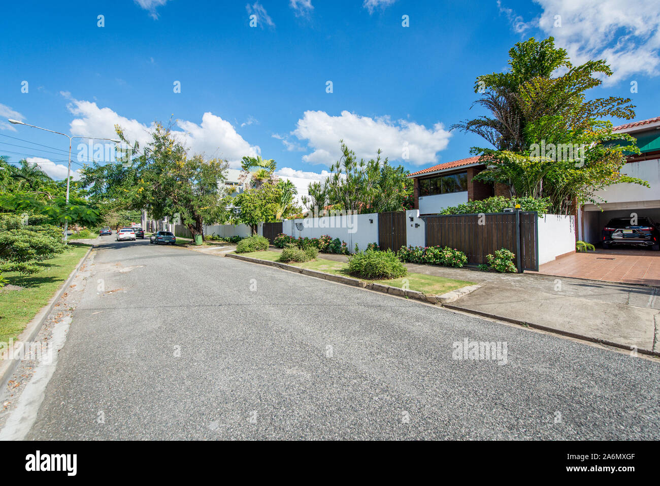 Punta Cana, Repubblica Dominicana; 11 aprile 2014: Strada asfaltata con poco traffico automobilistico, con giardinieri sui marciapiedi e le divisioni di strada con alberi Foto Stock
