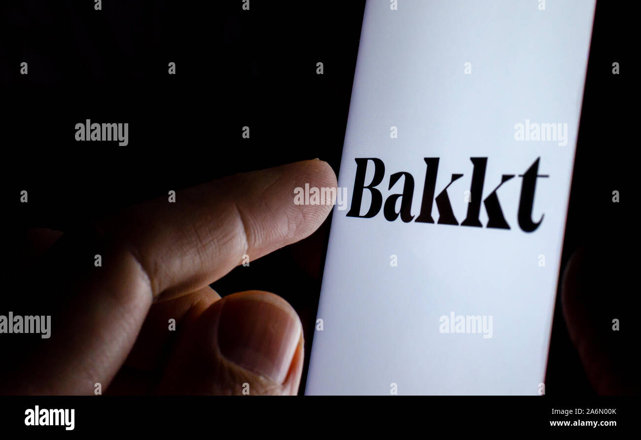 Bakkt company logo sullo schermo dello smartphone in una stanza buia e un dito puntato a. Bakkt è noto per Bakkt Bitcoin contratti Futures trading. Foto Stock