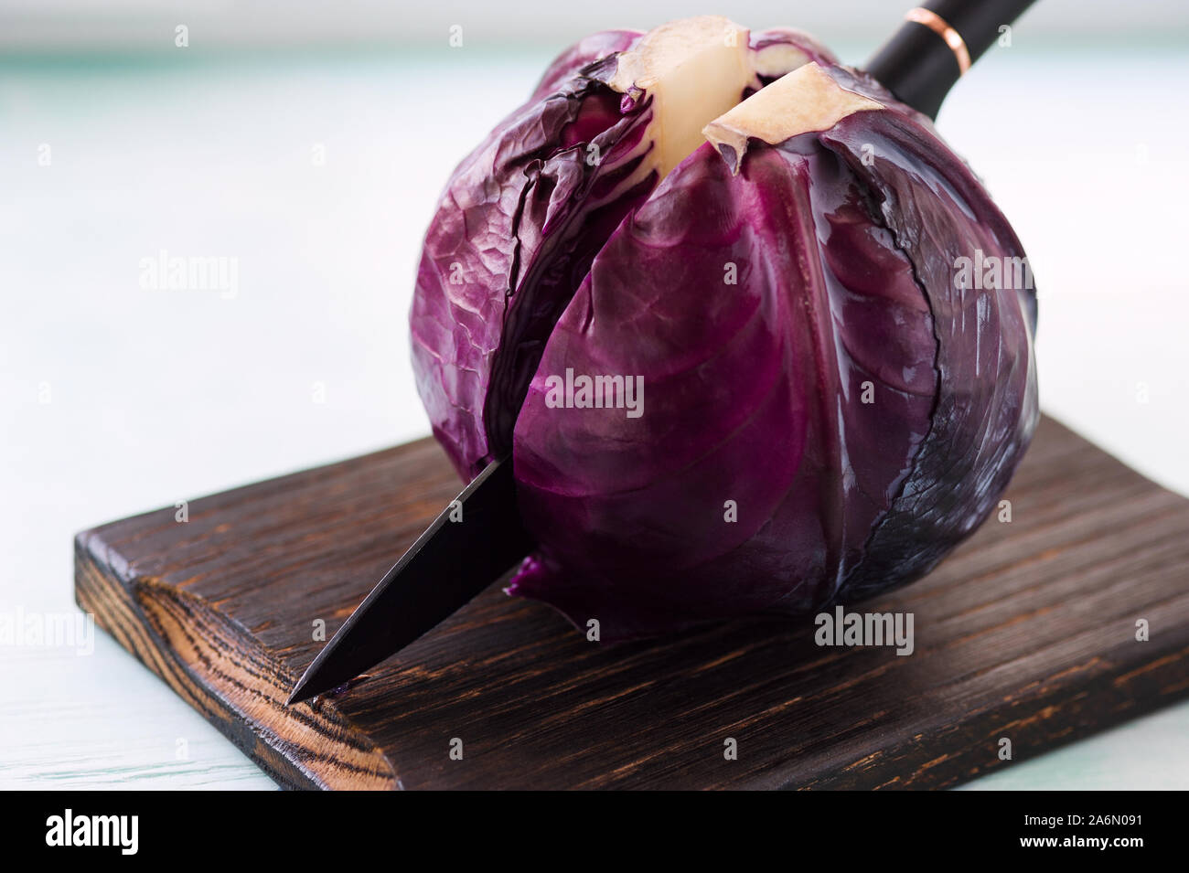 Fresco di cavolo rosso sul tagliere tagliato a metà con un coltello. Preparazione per il taglio per la cottura di viola insalata di cavolo o coleslaw. Concetto di cibo. Foto Stock