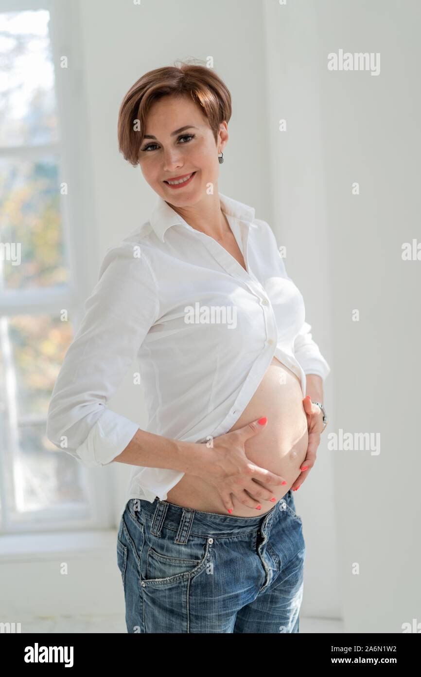 Una donna incinta trattiene il suo ventre con le mani Foto Stock