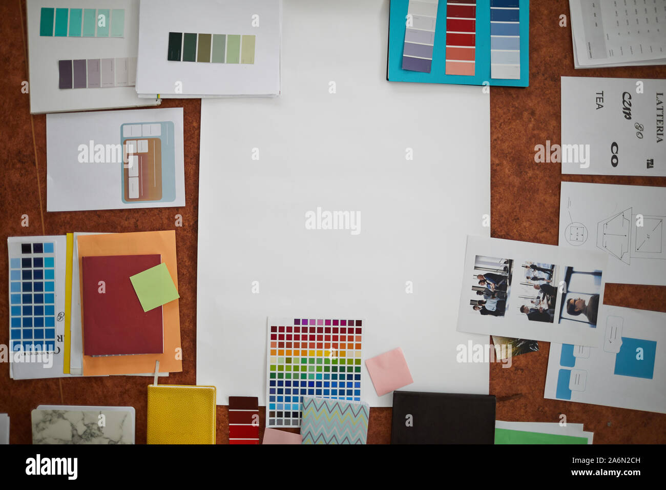 Al di sopra di vista di progettisti creativi sul posto di lavoro: i campioni di colore, tipo note e fotografie disposte su un tavolo di legno intorno a fogli di carta bianca, spazio di copia Foto Stock