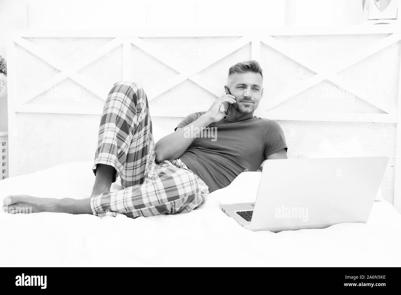 Il lavoro remoto concetto. Le reti sociali. Mondo online. L'uomo navigando in internet lavorare online. Già al lavoro. Il marketing digitale. Accesso remoto. Hipster barbuto RAGAZZO PIGIAMI lavoratore freelance in un momento di relax a casa. Foto Stock