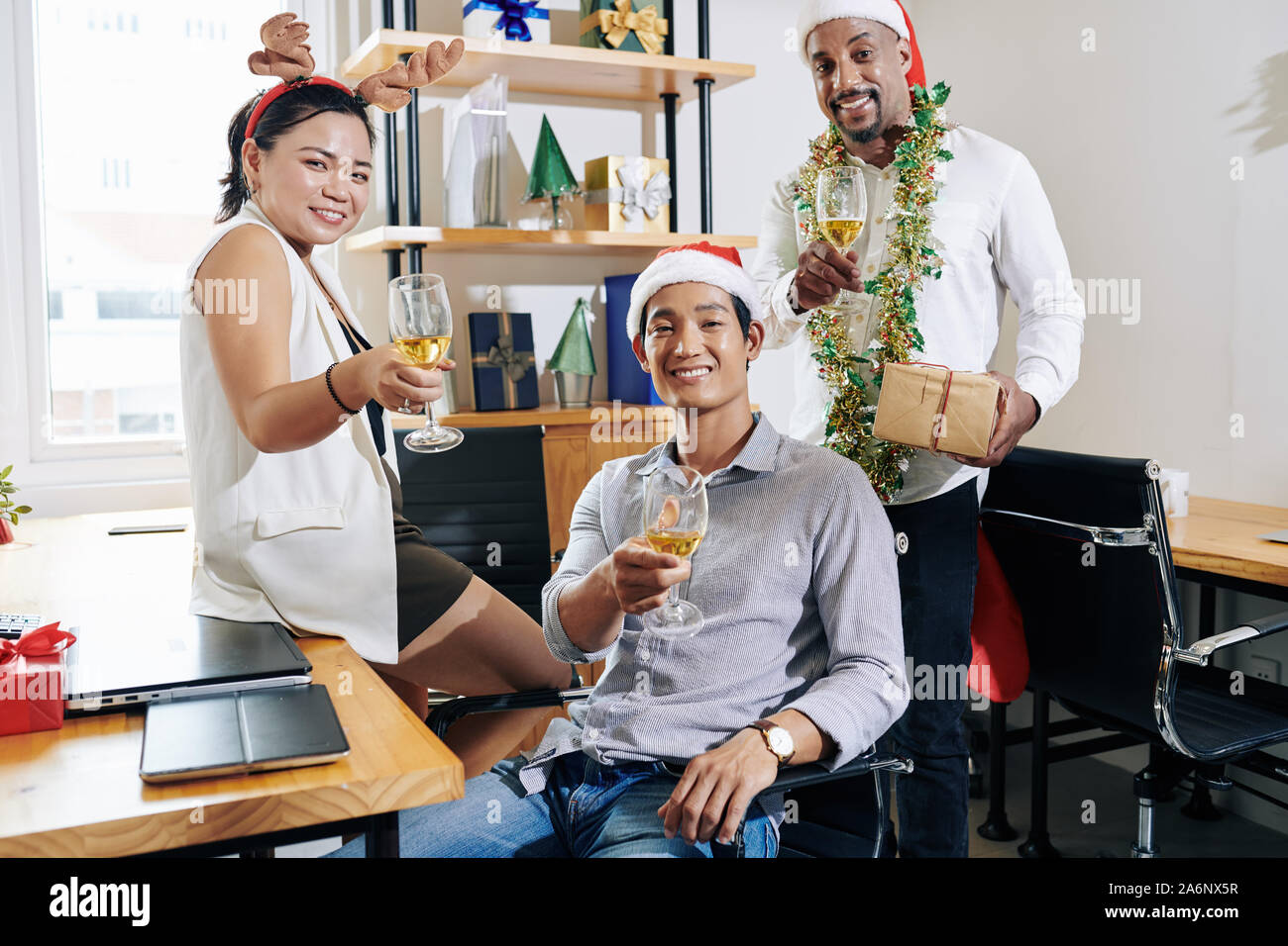 Multi-etnico team business indossando cappelli di Babbo Natale e renne palchi quando godendo di festa di Natale alla small office Foto Stock
