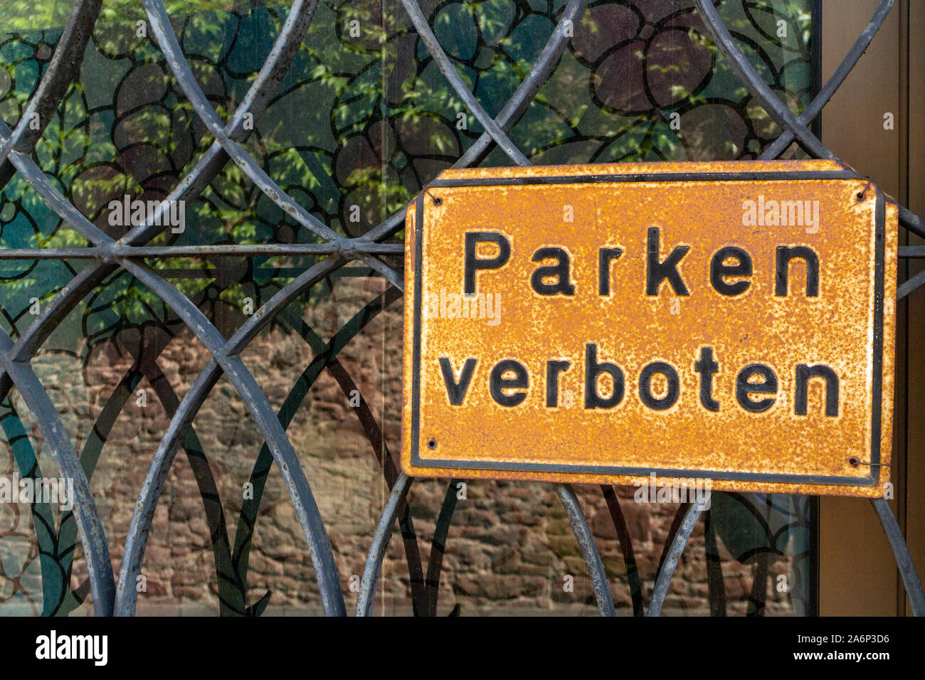 Vecchio weathered e rusty segno davanti a una finestra con il vecchio decorativo griglia in metallo con le parole "Parken verboten' che significa 'nessun parcheggio' in tedesco l Foto Stock