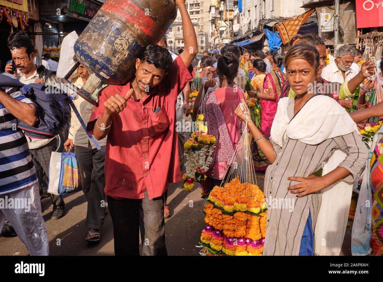 Un uomo di erogazione di una bombola di gas passa rivenditori di calendula fiori vicino Phul Galli (Fiore Lane) in area Bhuleshwar, Kalbadevi, Mumbai, India Foto Stock