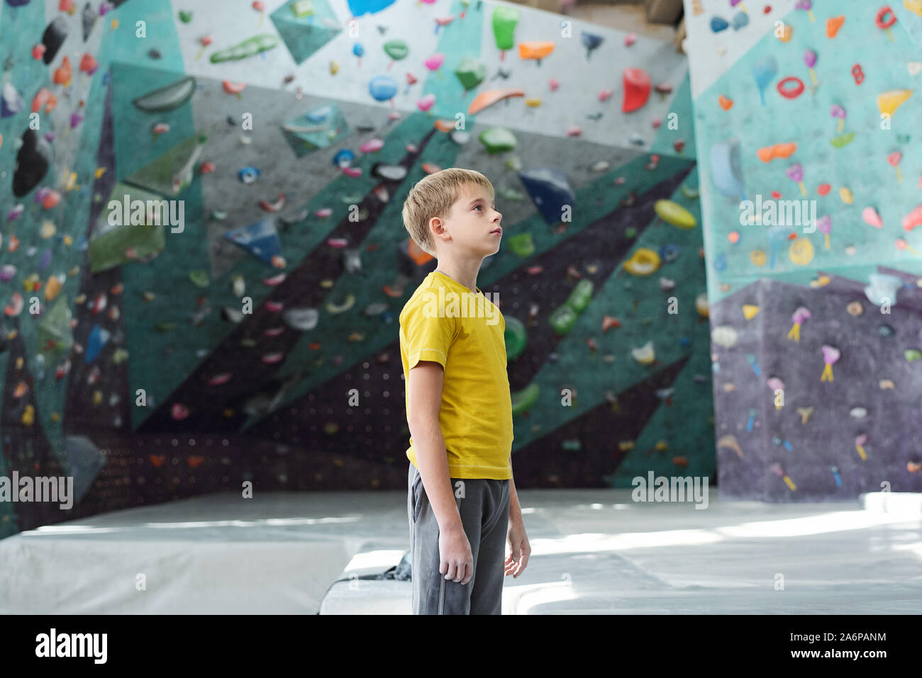 Giovanissimo sportivo in activewear in piedi nel centro della sala di arrampicata Foto Stock