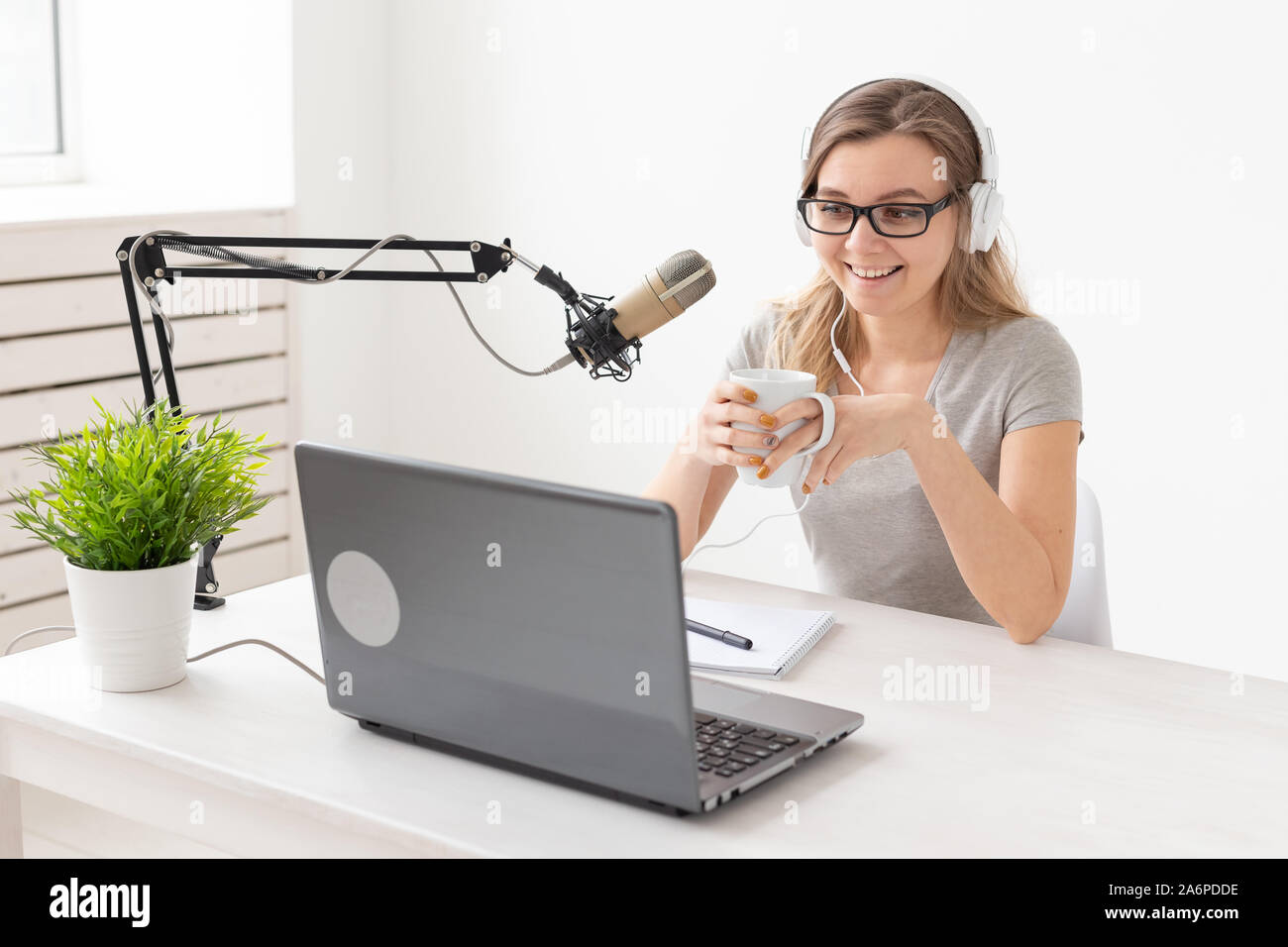 Radio, DJ, blogging e concetto di persone - donna sorridente seduto davanti a un microfono, host a radio Foto Stock