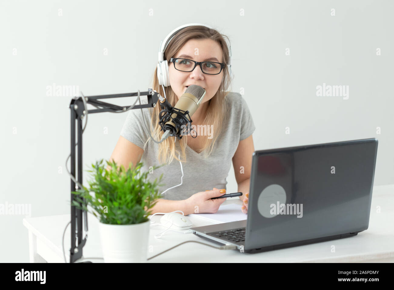 Radio, DJ, blogging e concetto di persone - donna sorridente seduto davanti a un microfono, host a radio Foto Stock