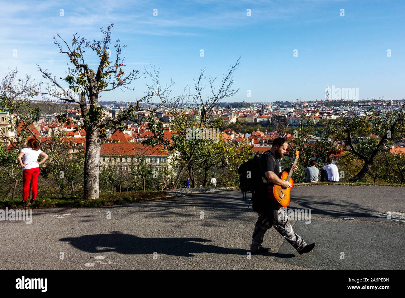 L'uomo con una chitarra attraversa il parco in una giornata di sole Praga Petrin Hill Park Foto Stock