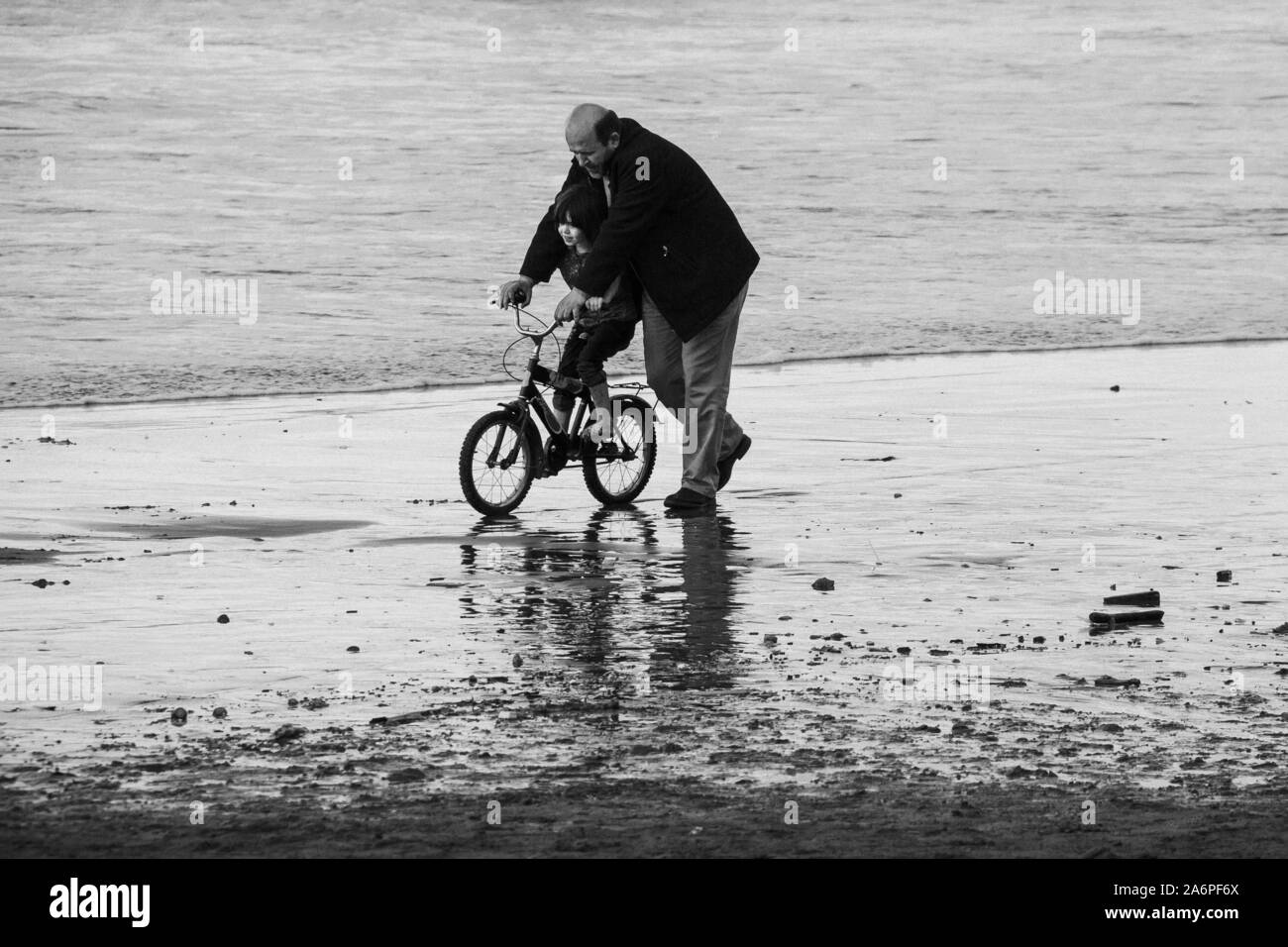 Una bella scena di un padre e figlia in una città costiera a nord dell'Iran. Papà è insegnamento in sella ad una bicicletta per il suo bambino e sono entrambi avendo divertimento. Foto Stock