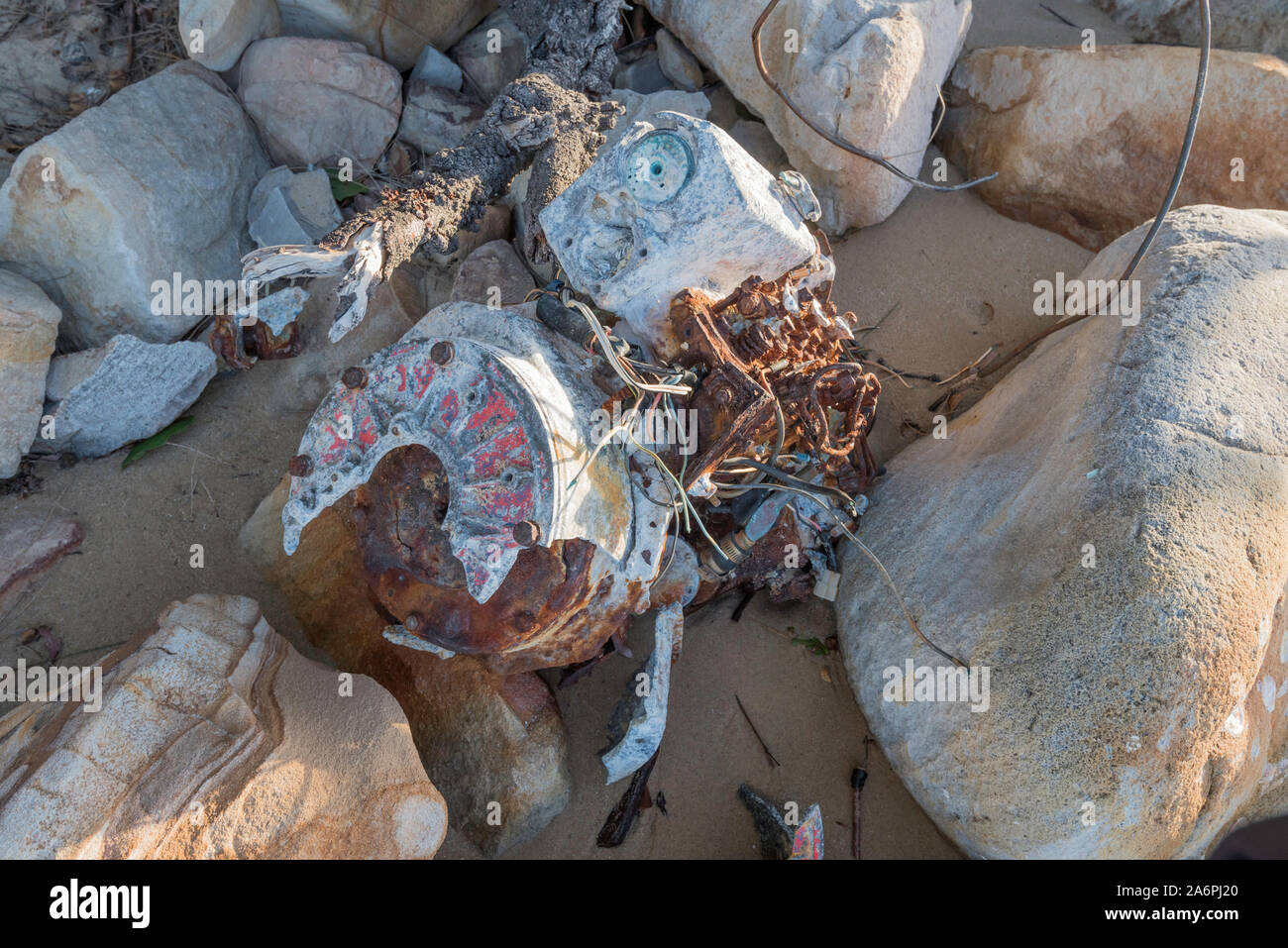 Un mezzo sepolto barca motore giace arrugginimento e corrosione nella sabbia tra le rocce su una spiaggia vicino Bundeena nel sud di Sydney, Australia Foto Stock
