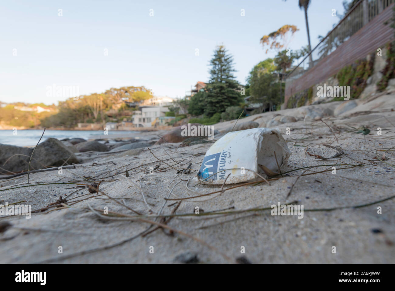 Sulla altrimenti incontaminata spiaggia di Sydney un parzialmente degradato Styrofoam McDonalds cup giace lavato fino sulla sabbia a Bundeena, Australia Foto Stock
