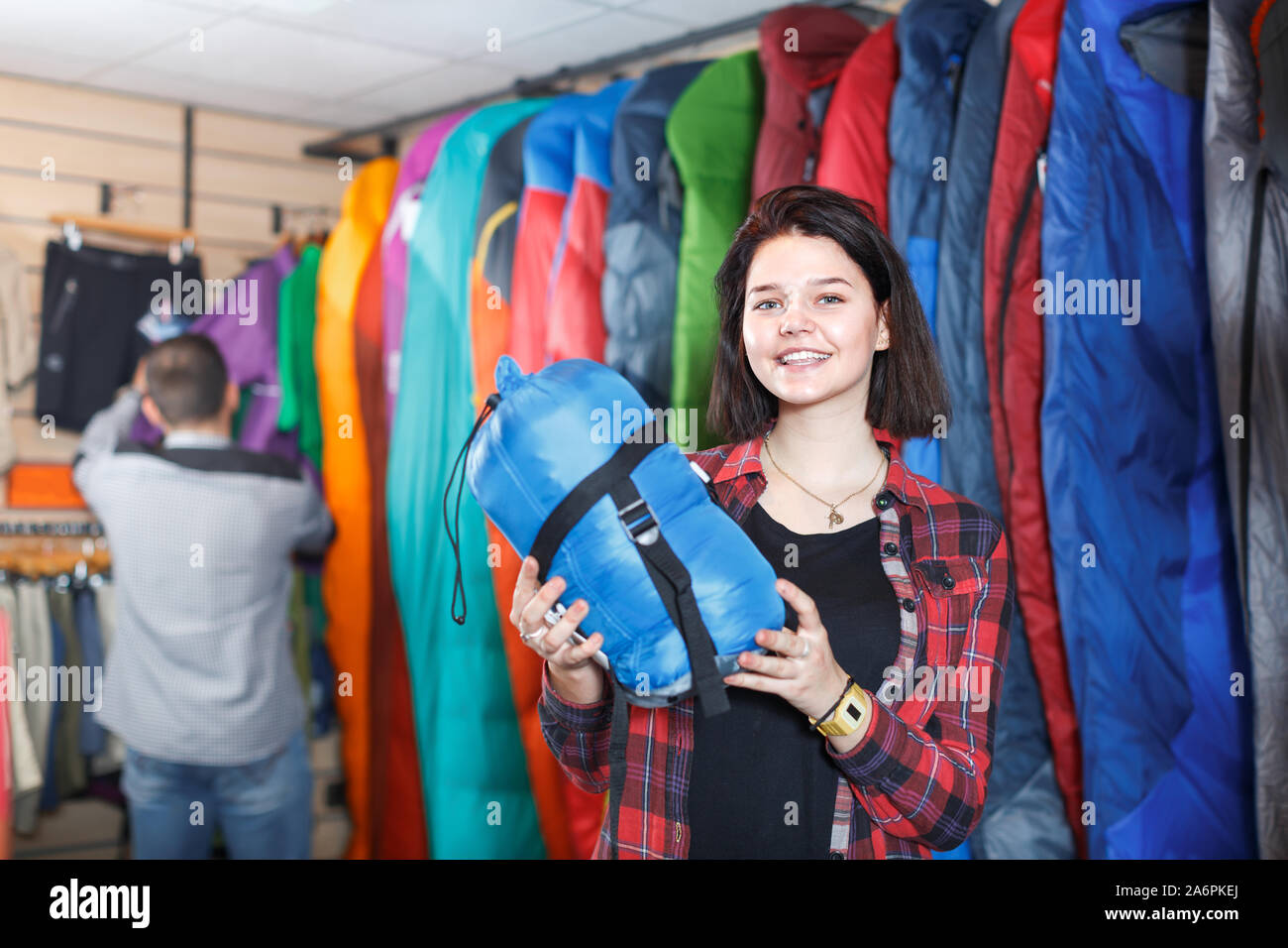 Giovani femmine cliente esaminando i sacchi a pelo in negozio per articoli sportivi Foto Stock