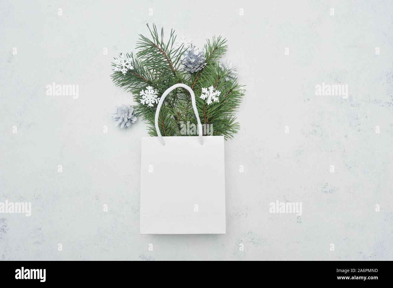 Natale mock up lay piatto con pacchetto bianco e abete e fiocchi di neve in bianco sullo sfondo di legno. Composizione moderna per vacanze inverno design Foto Stock