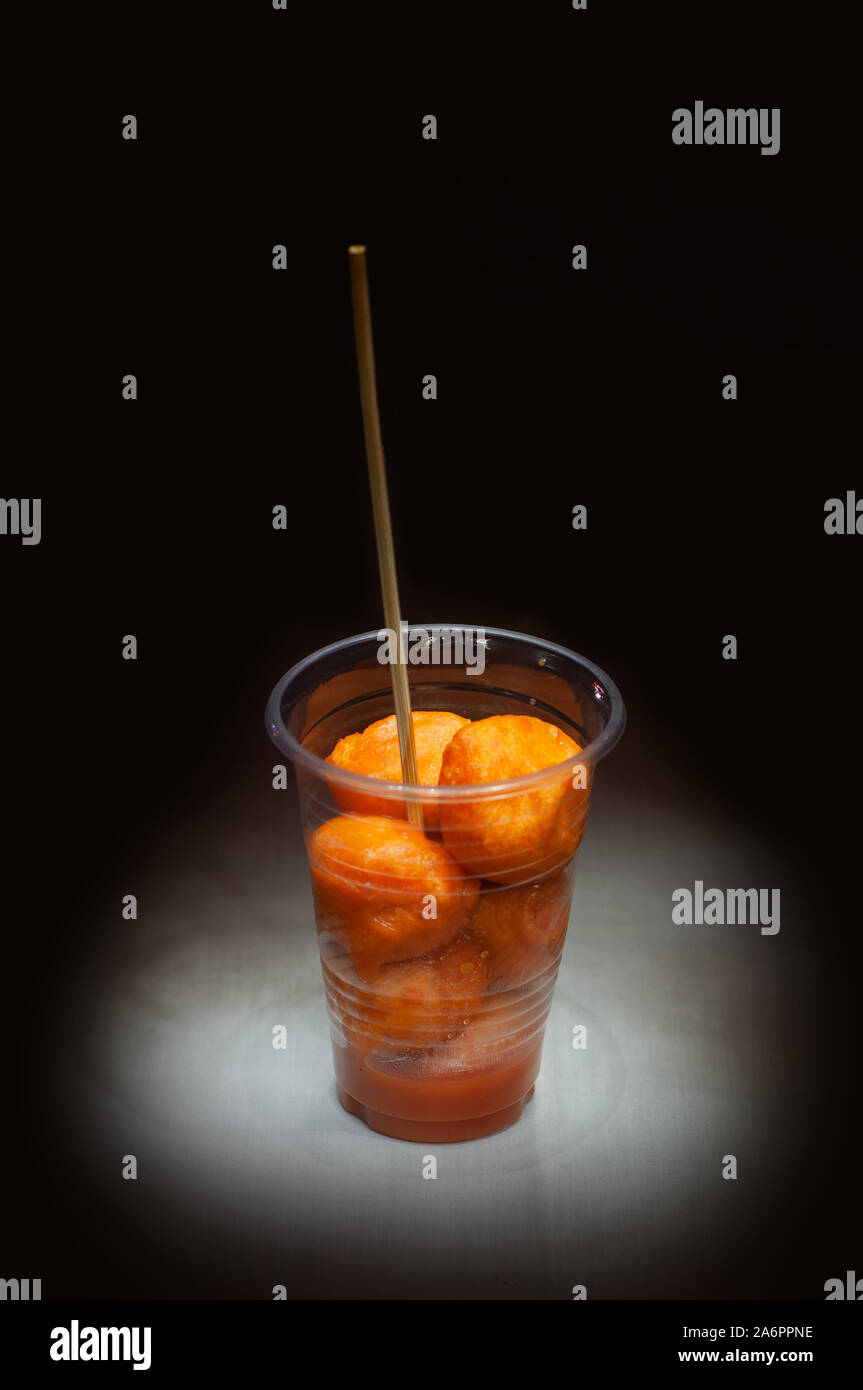 Kwek, nella - Kwek, nella / Tokneneng - un filippino tempura-come cibo di strada in una tazza di plastica con il bastone in nero lo sfondo isolato. Foto Stock