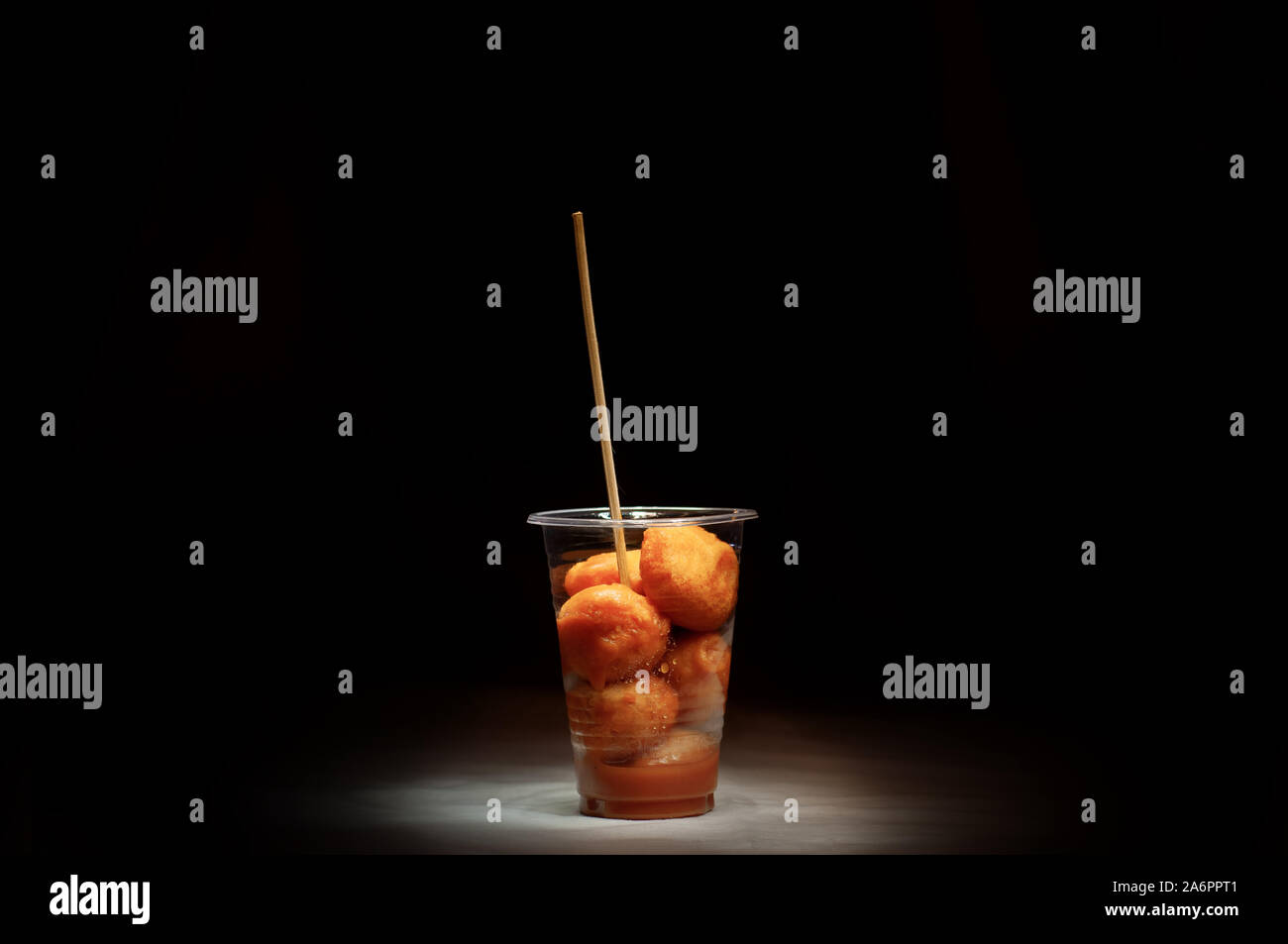 Kwek, nella - Kwek, nella / Tokneneng - un filippino tempura-come cibo di strada in una tazza di plastica con il bastone in nero lo sfondo isolato. Foto Stock