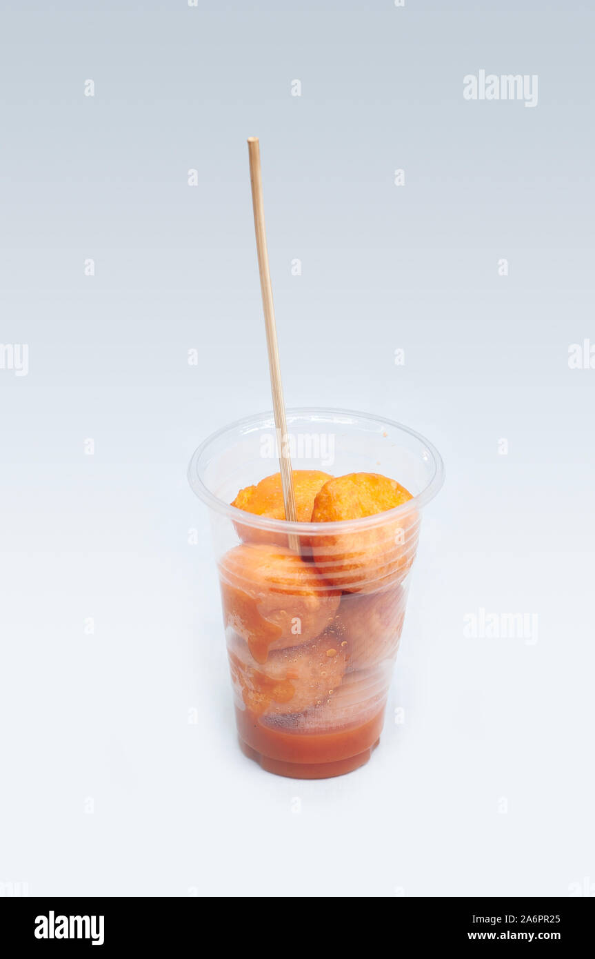 Kwek, nella - Kwek, nella / Tokneneng - un filippino tempura-come cibo di strada in una tazza di plastica con il bastone in bianco sullo sfondo isolato. Foto Stock
