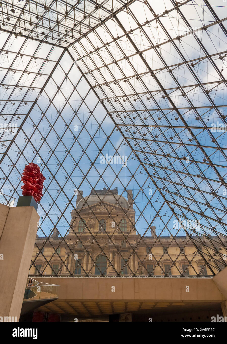 Una grande visualizzazione verticale dell'Ala Richelieu attraverso il vetro della piramide del Louvre a Parigi dalla metropolitana lobby con la scultura rosso contro di... Foto Stock