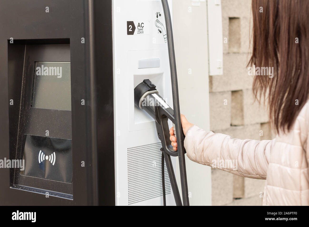 Donna uso elettrico caricabatteria rapido per apparecchiature elettriche o di automobili ibride. Alta tecnologia caricabatteria per strada verde di guida di PHEV. Ecologia friendly caricabatterie Foto Stock