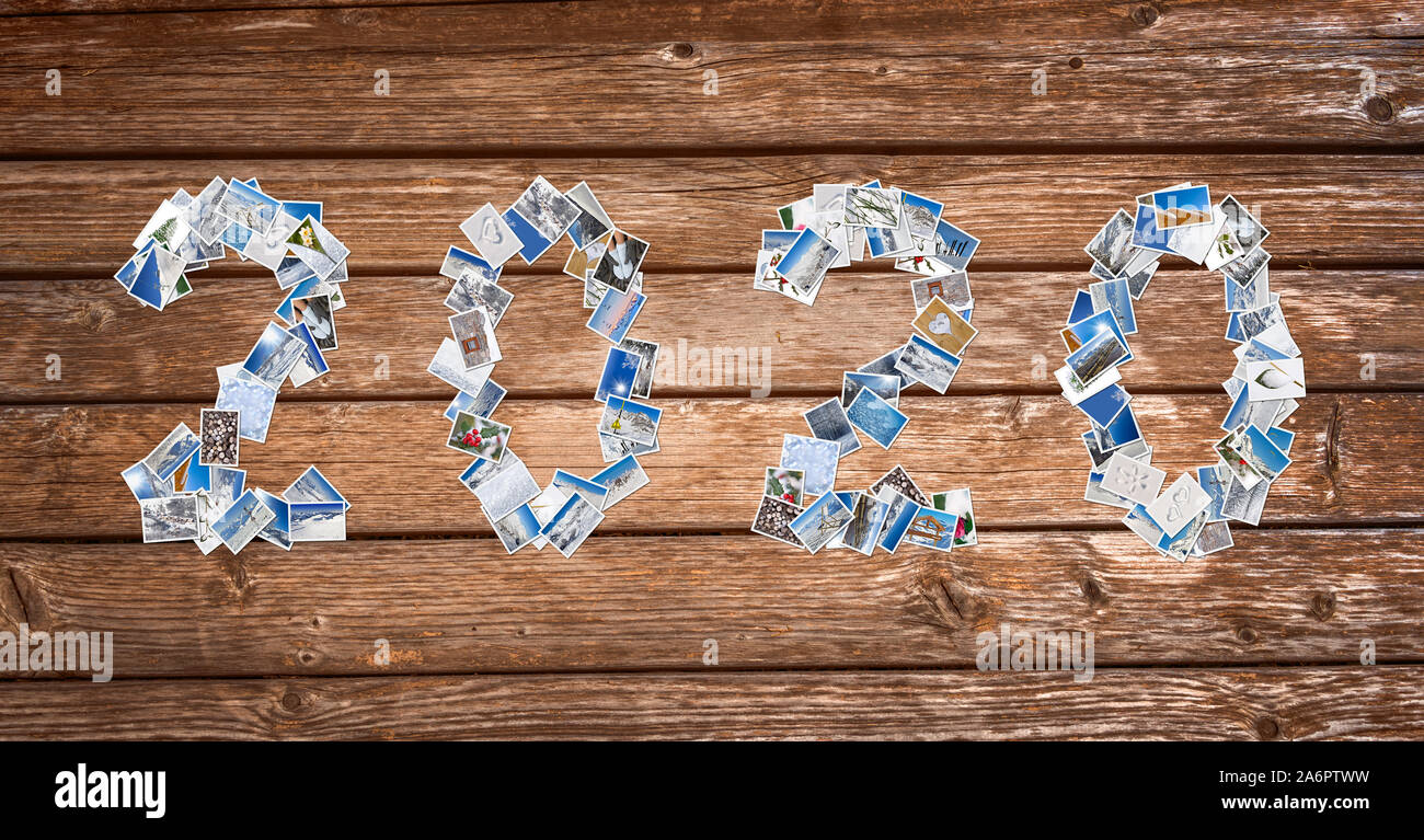 2020, neve e inverno pila di foto su tavole di legno sfondo, anno nuovo card Foto Stock