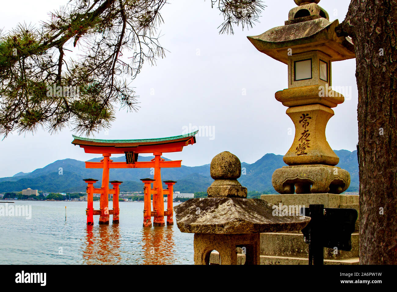 Giapponese lanterne di pietra con la floating torii gate del santuario di Itsukushima nel mare di Miyajima island, Giappone Foto Stock