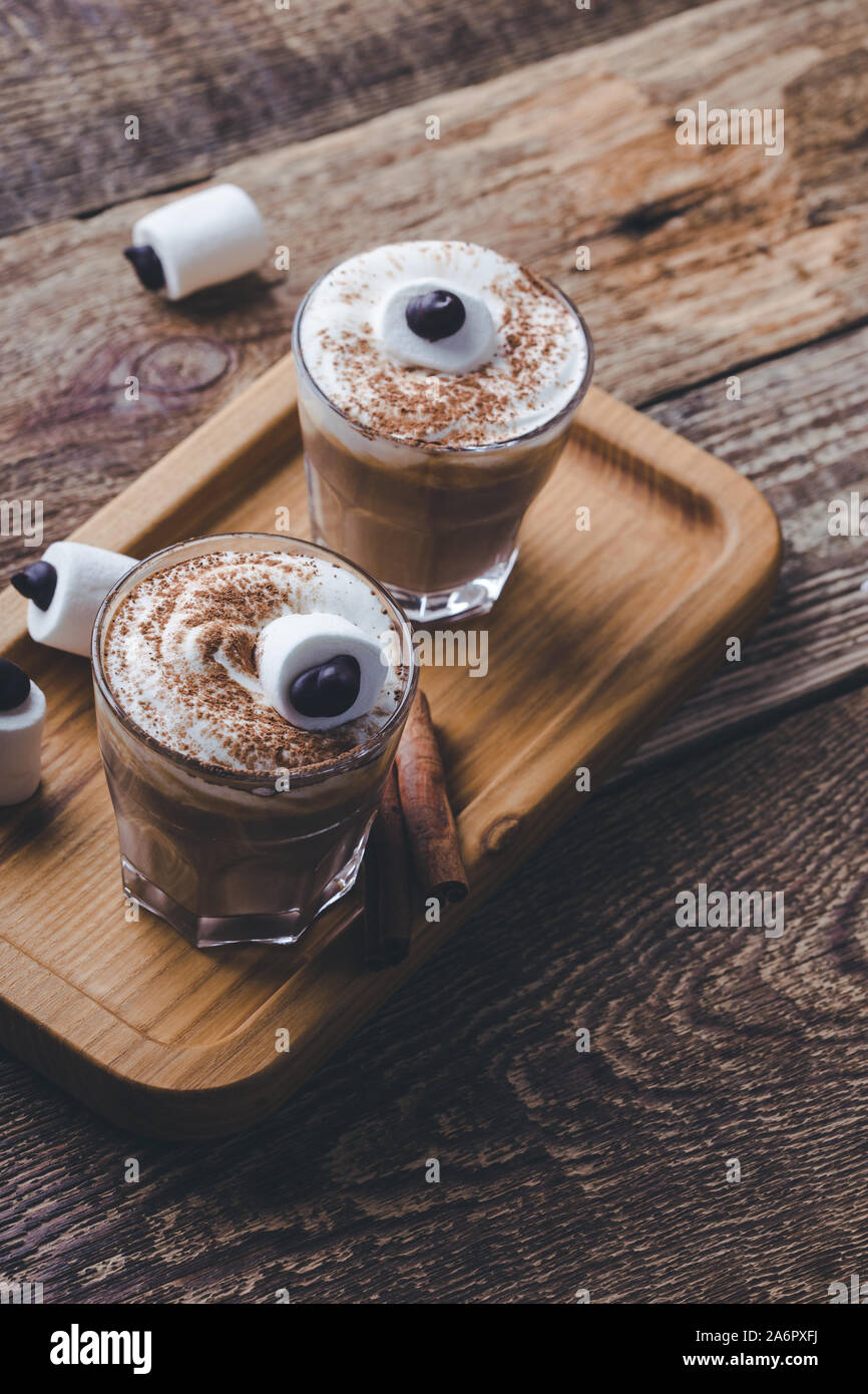 Happy Halloween monster, pumpkin spice latte con panna montata e grandi occhi marshmallow sulla parte superiore, Halloween dessert in bicchieri Foto Stock