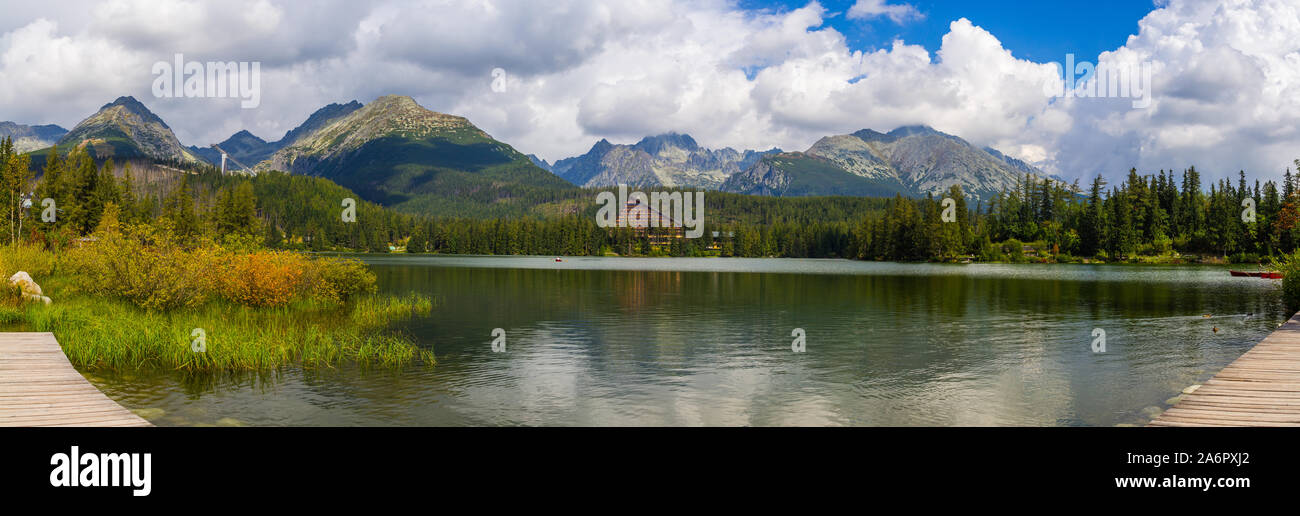 Grandioso panorama di montagna lago ferrovia Štrba, con Alti Tatra sullo sfondo. Vi è una ski jumping hill, nuoto anatre vicino alla costa del lago Foto Stock