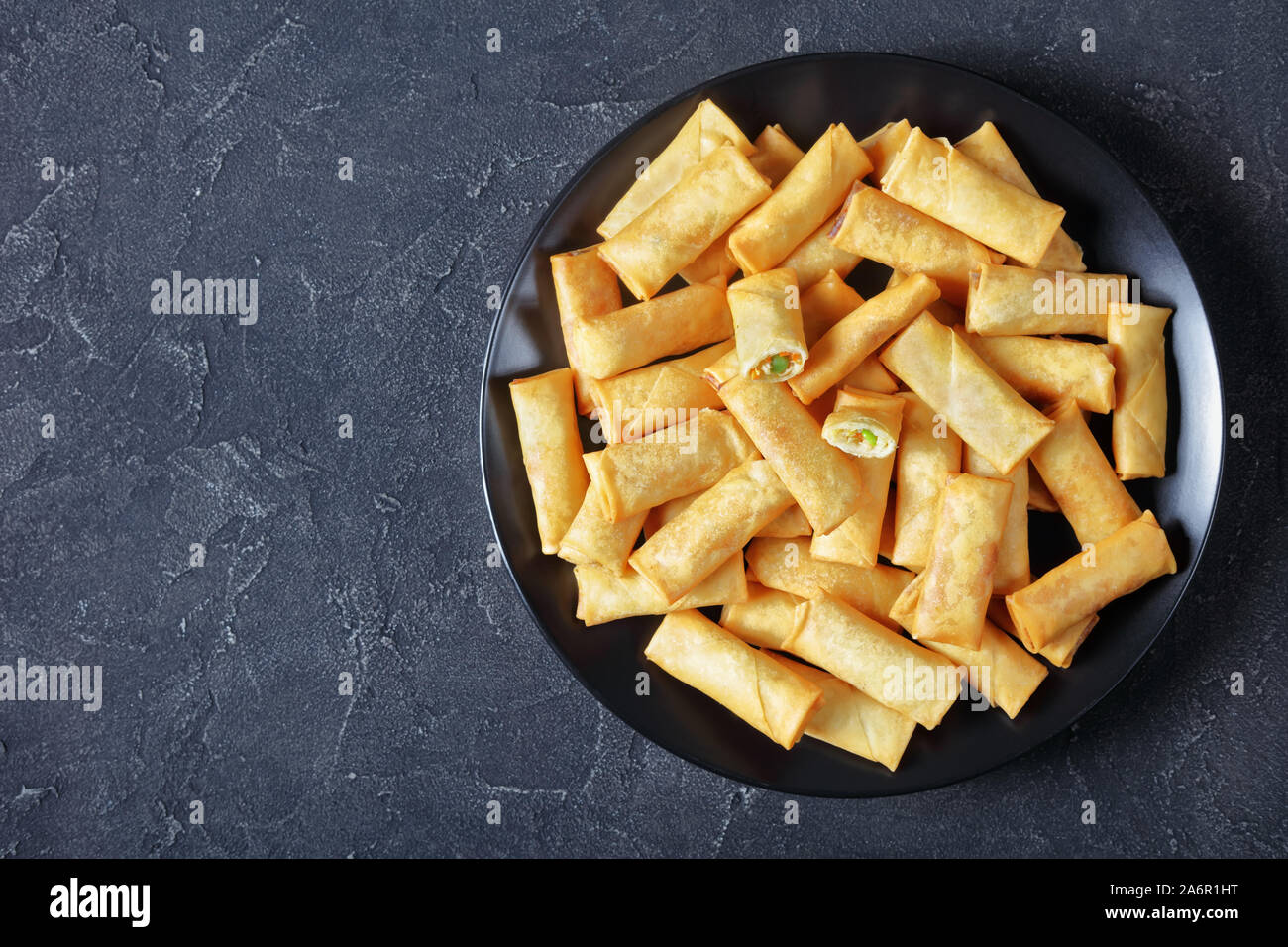 Fritte cinese Croccanti involtini primavera con verze, carote e piselli verdi ripieni su una piastra nera su una tavola di cemento, vista da sopra, flatlay, f Foto Stock