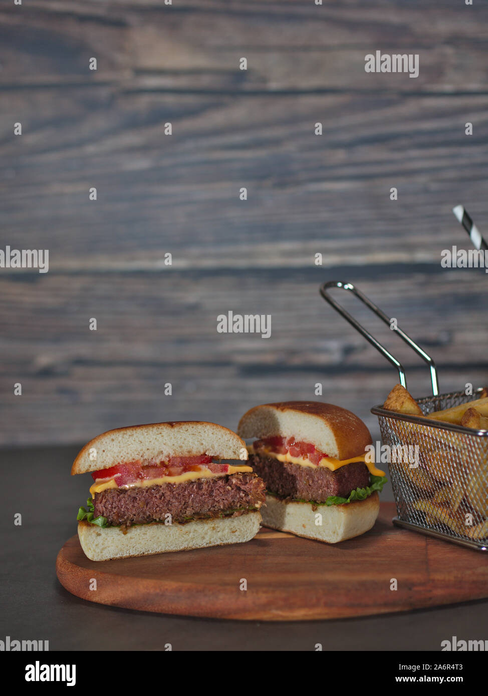 Vegan impianto basato burger tagliato a metà con patate fritte servite su vassoio in legno Foto Stock