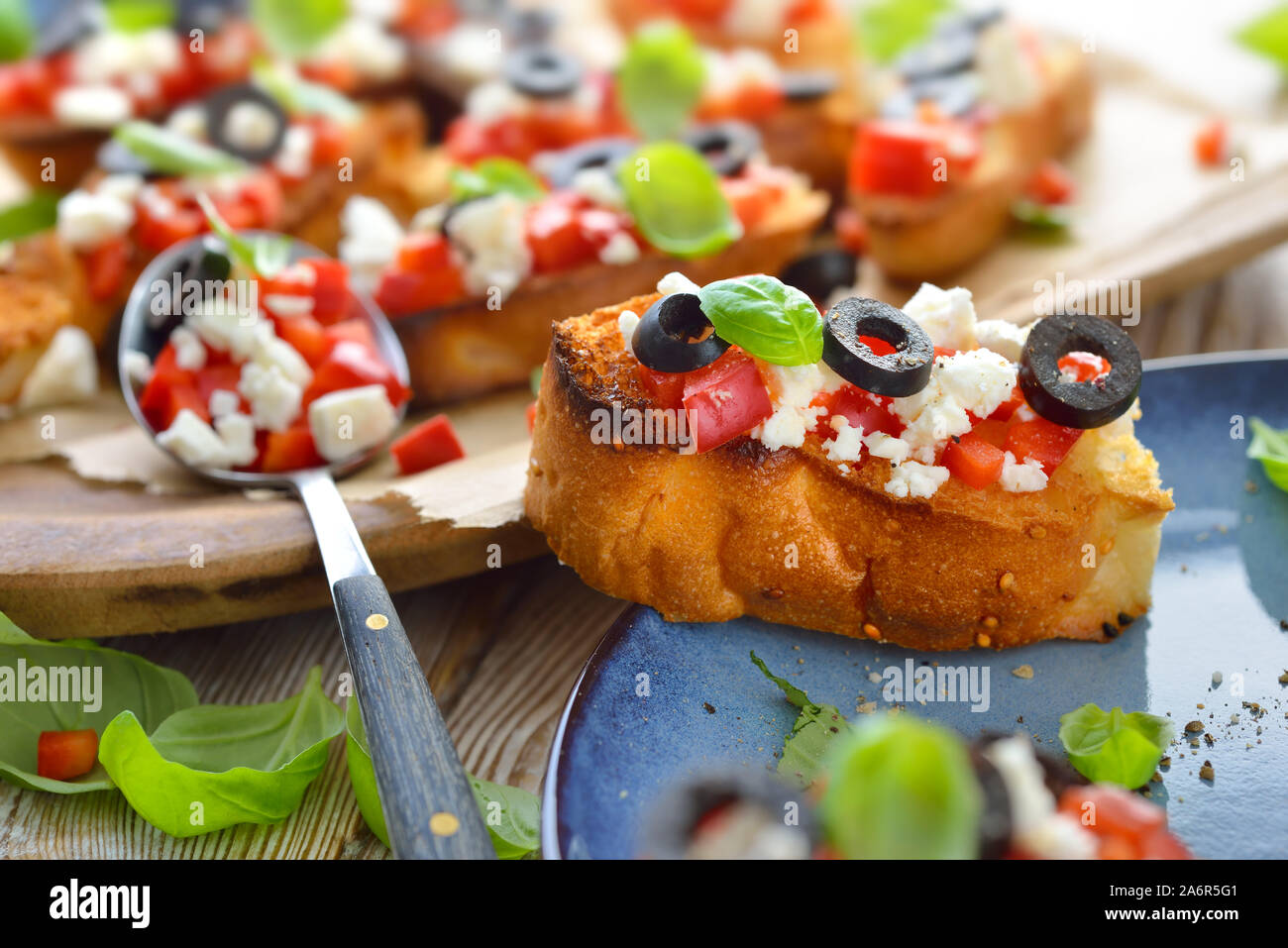 Calda bruschetta greca: croccante cotta piccole fette di pane pita con il formaggio feta, olive nere, peperoncino e basilico, servita come antipasto Foto Stock