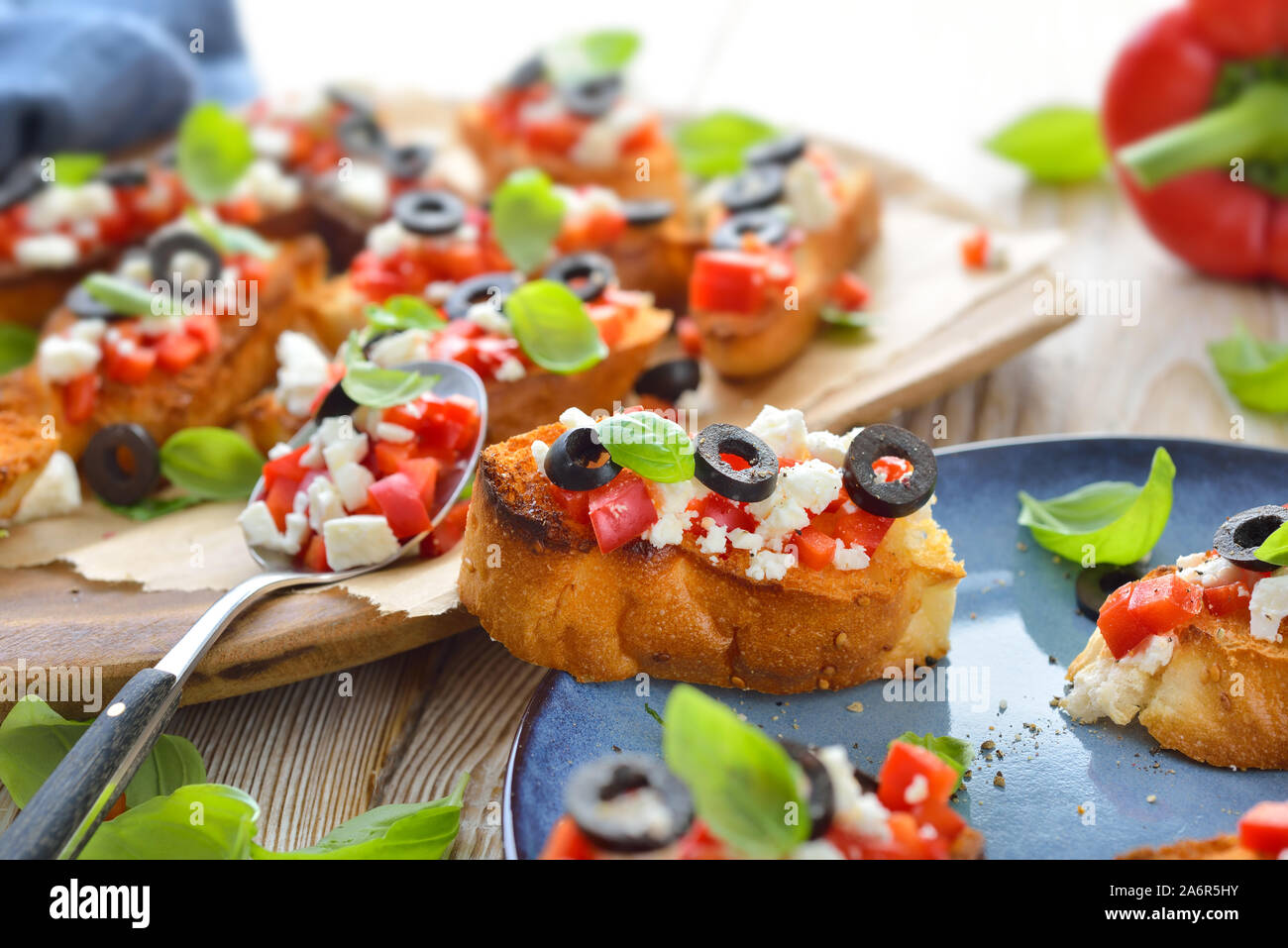 Calda bruschetta greca: croccante cotta piccole fette di pane pita con il formaggio feta, olive nere, peperoncino e basilico, servita come antipasto Foto Stock