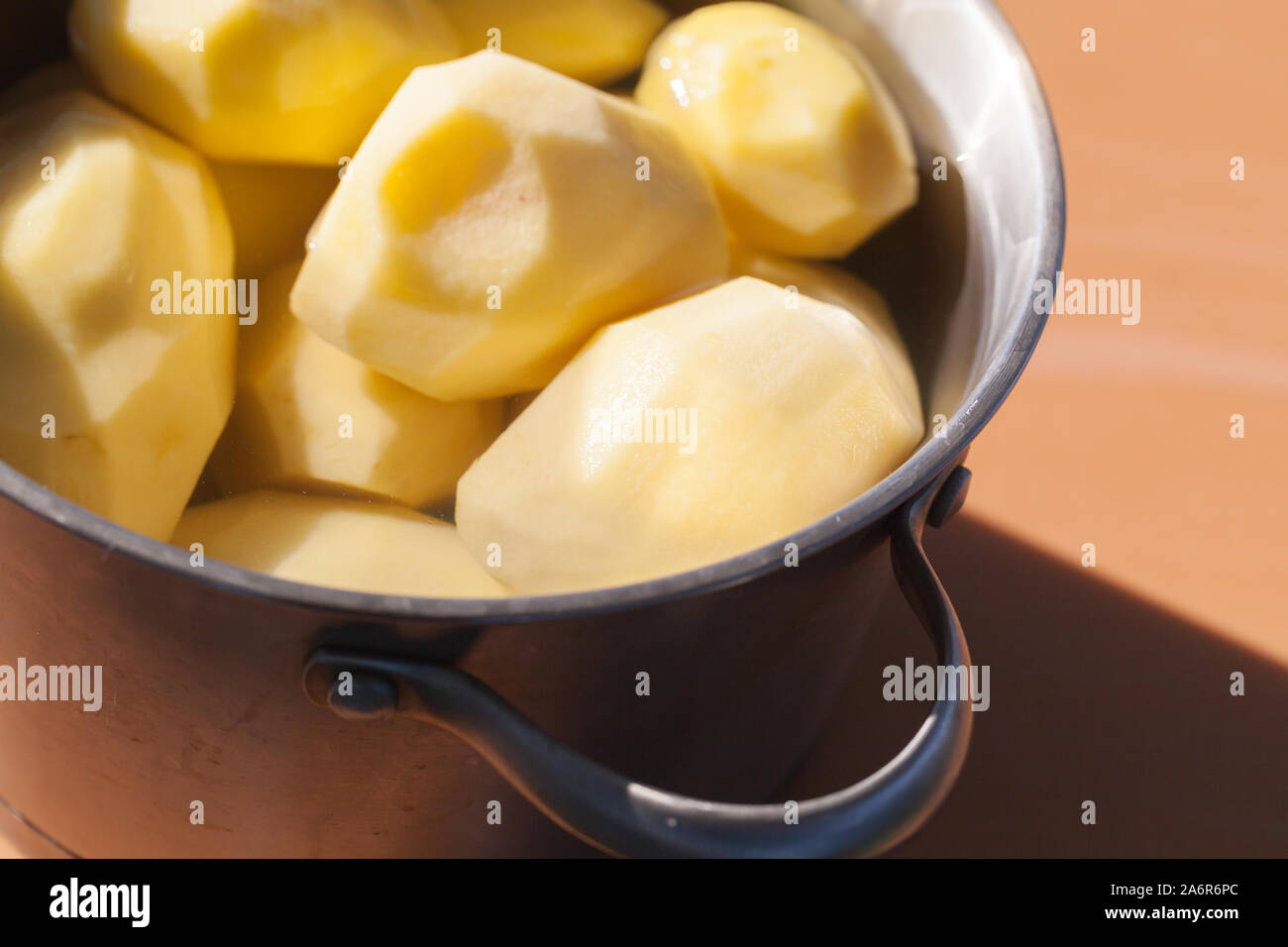 Materie di patate pelate i laici in tondo piatto in acciaio inossidabile con acqua, close-up foto con messa a fuoco selettiva Foto Stock