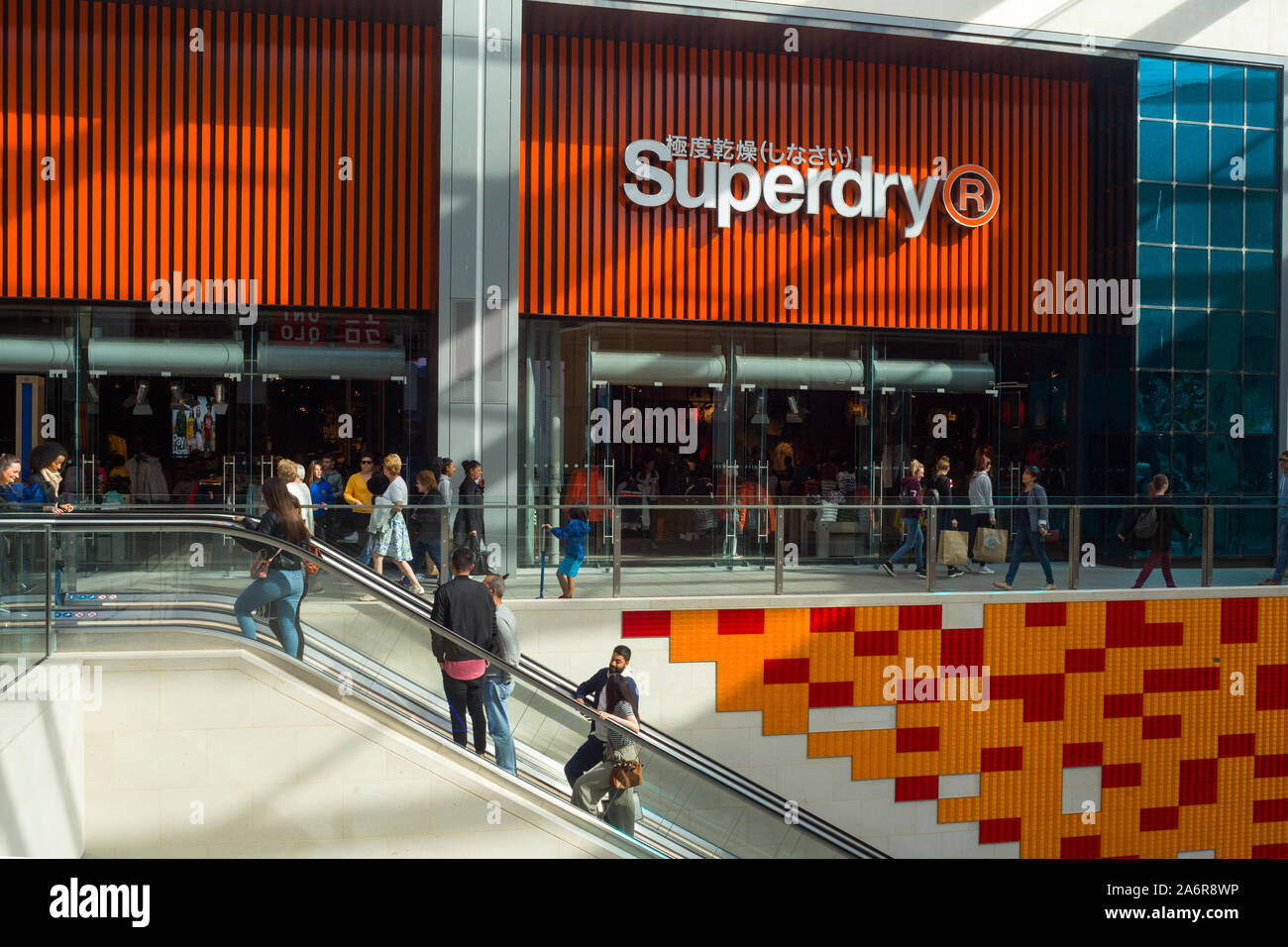 Gli amanti dello shopping salire la scala mobile nella parte anteriore del negozio Superdry in Westgate Shopping Center, Oxford Foto Stock