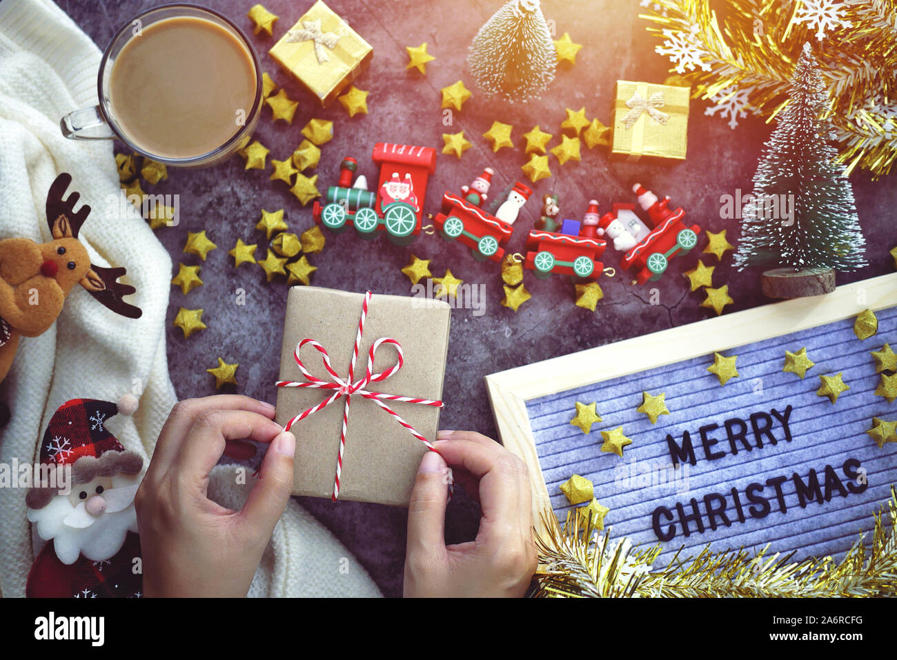 Mano Messa a prua per legare la confezione regalo, wrap presente per la stagione di natale e festival regalo decorazioni con ornamento di Natale sul tavolo Foto Stock