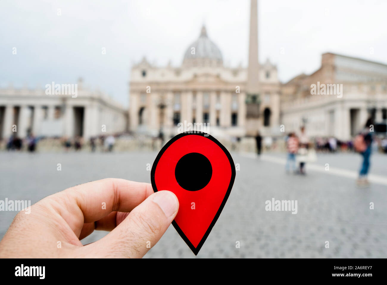 Primo piano della mano di un uomo caucasico tenendo un contrassegno rosso presso la famosa Basilica di San Pietro in Vaticano, Italia Foto Stock