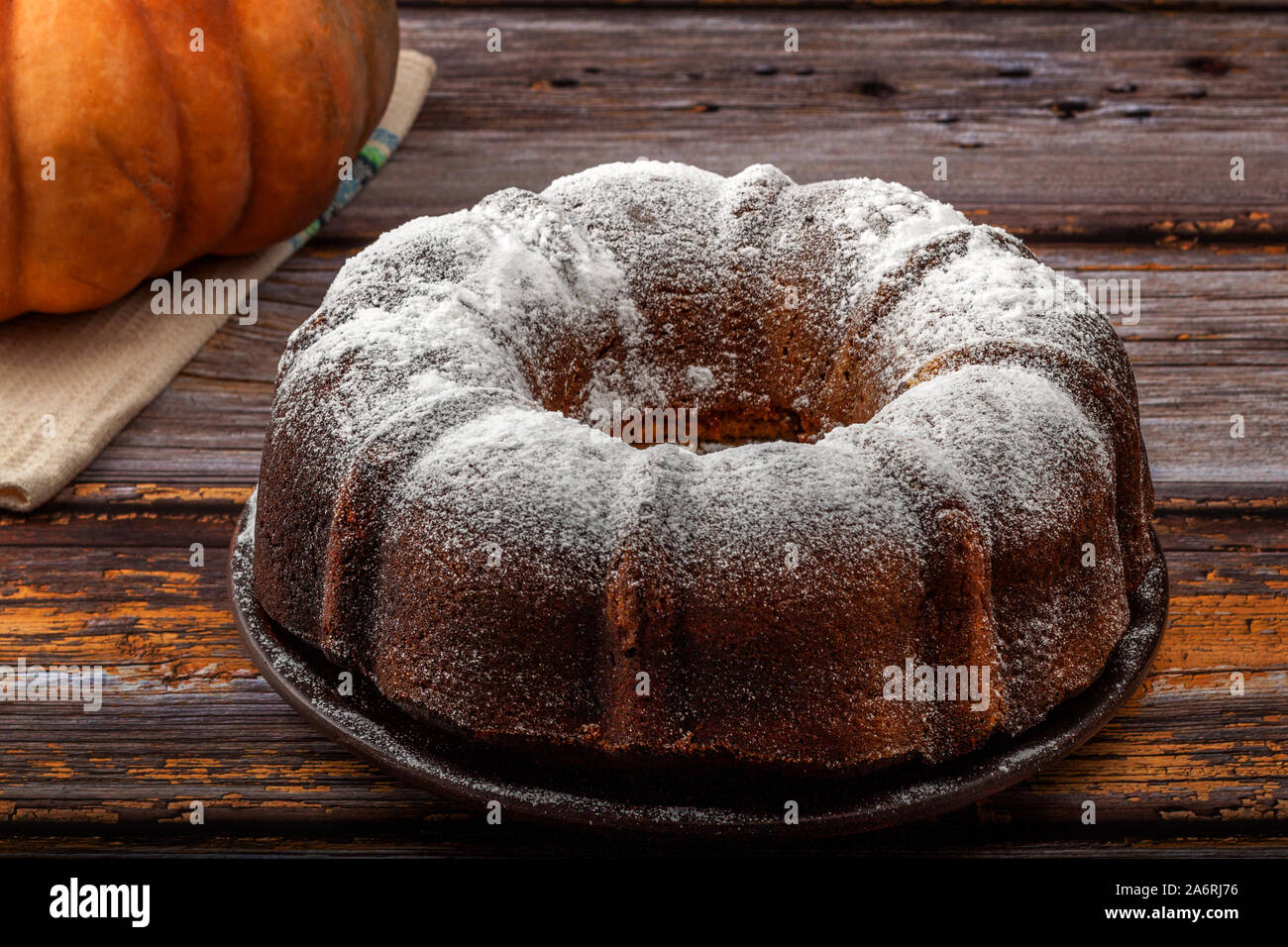 Muffin di zucca al buio su un tavolo in legno e zucca in background Foto Stock