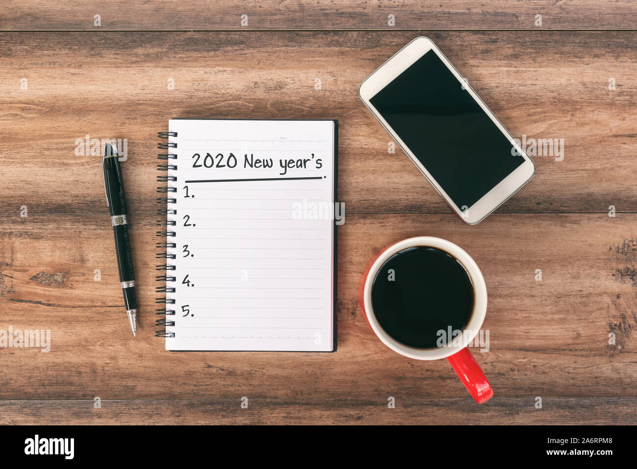 Anno nuovo concetto - 2020 Numero e testo in Blocco note. Smartphone, penna e la tazza di caffè sfondo. Foto Stock