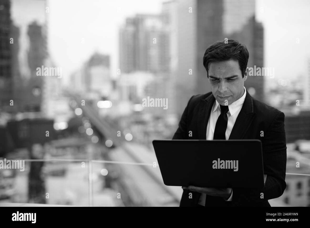 Bello imprenditore persiano contro la vista della città in nero a Foto Stock