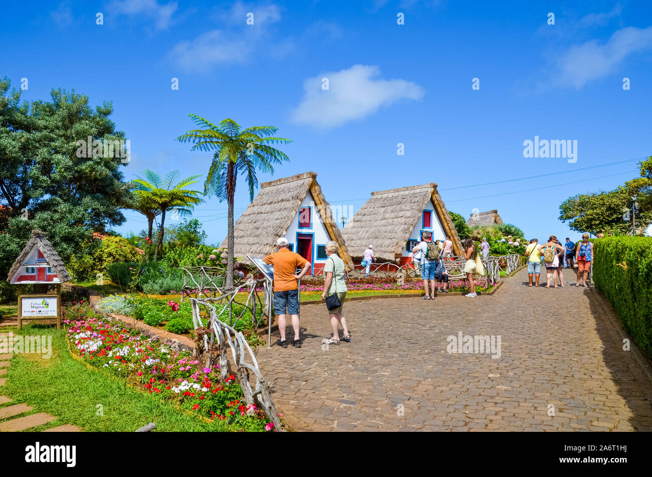 Santana, isola di Madeira, Portogallo - Sep 24, 2019: turisti ammirando tradizionali case colorate. Uno dei principali di Madeira luoghi turistici, patrimonio portoghese. Palme e fiori colorati, giornata di sole. Foto Stock