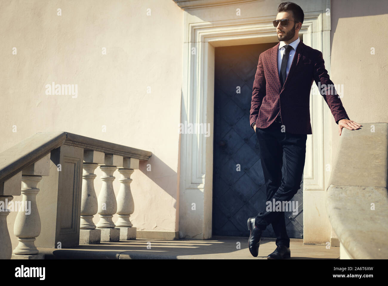 Elegante di moda uomo in nero occhiali da sole in posa all'aperto sulle scale (copia spazio). Foto Stock